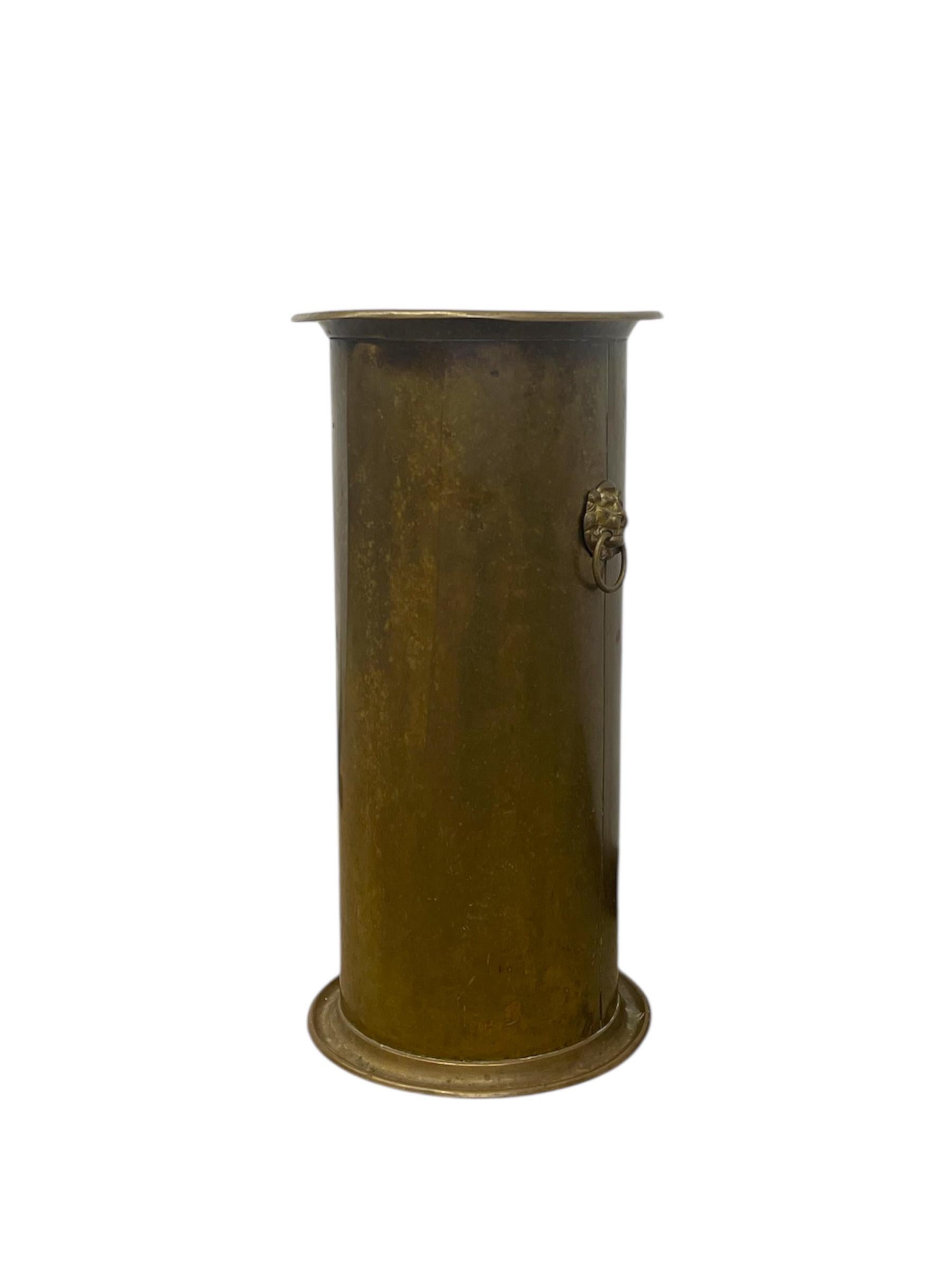 A stately and substantial English Regency-style umbrella stand crafted from brass, featuring a cylindrical form with flared lip and stepped base. The exterior retains a rich, naturally aged patina with areas of oxidation and light verdigris,