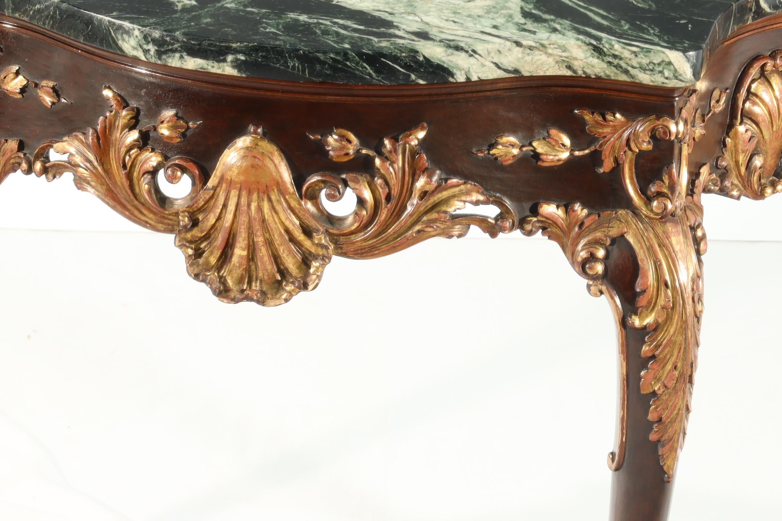 Vintage English reproduction of a George II carved mahogany and gilt console table with well-shaped front and dark green and white mottled marble top. The well-shaped cabriole legs terminated in finely carved claw and ball feet. A finely crafted