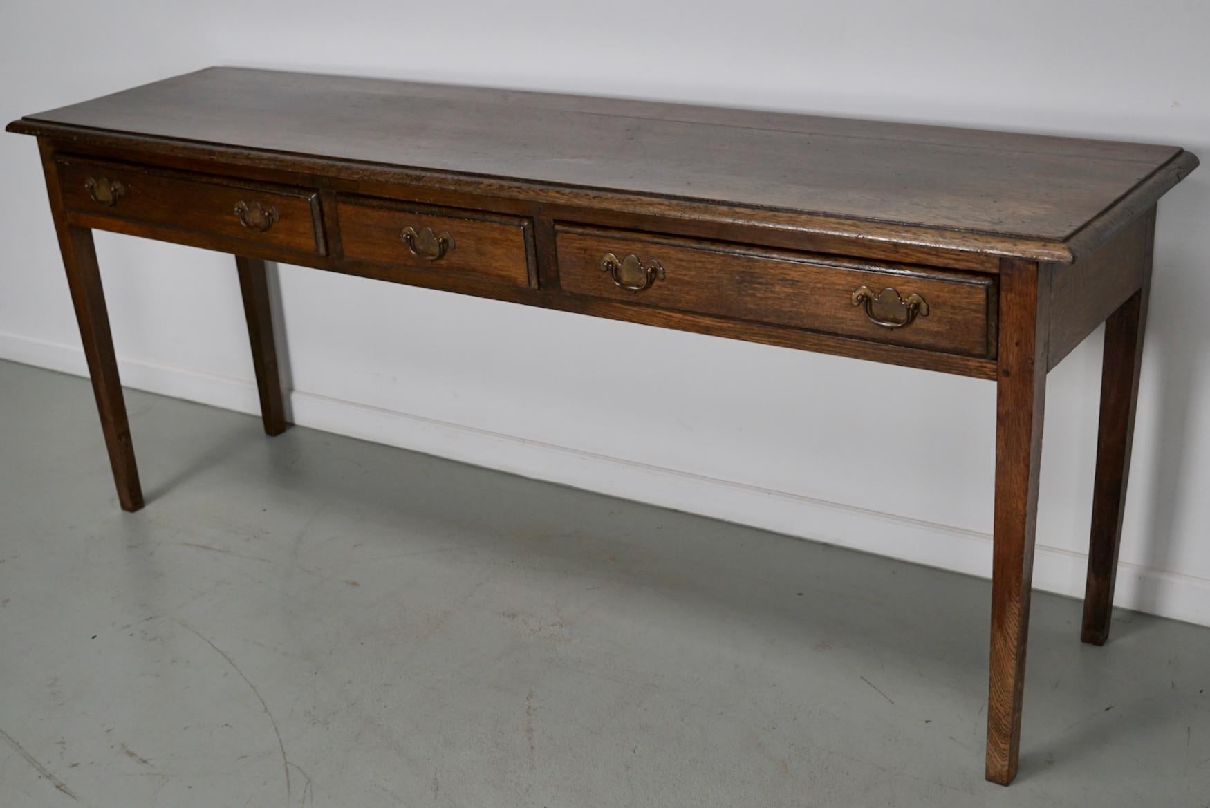 This elegant table was made in England. The table was made in solid oak with a beautiful grain pattern. It has a warm color with deep gloss. It was originally a dining table and later in it's life converted into this side table.