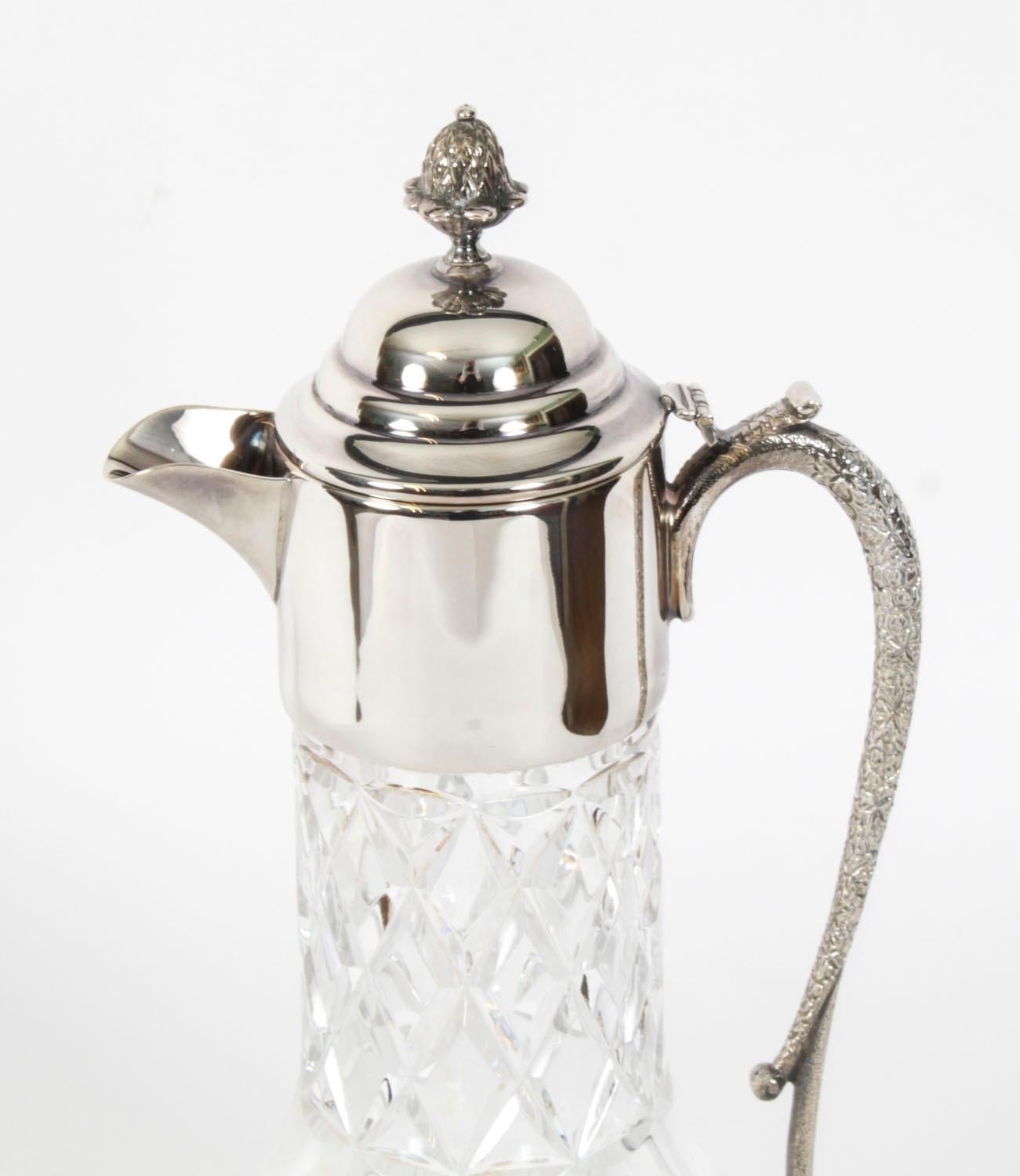 This is an elegant English vintage cut glass silver plated claret jug, dating from the late 20th Century.

The silver plate mounted claret jug features beautiful cut glass. The hinged lid with a pierced thumbpiece, a wonderful scroll cast silver