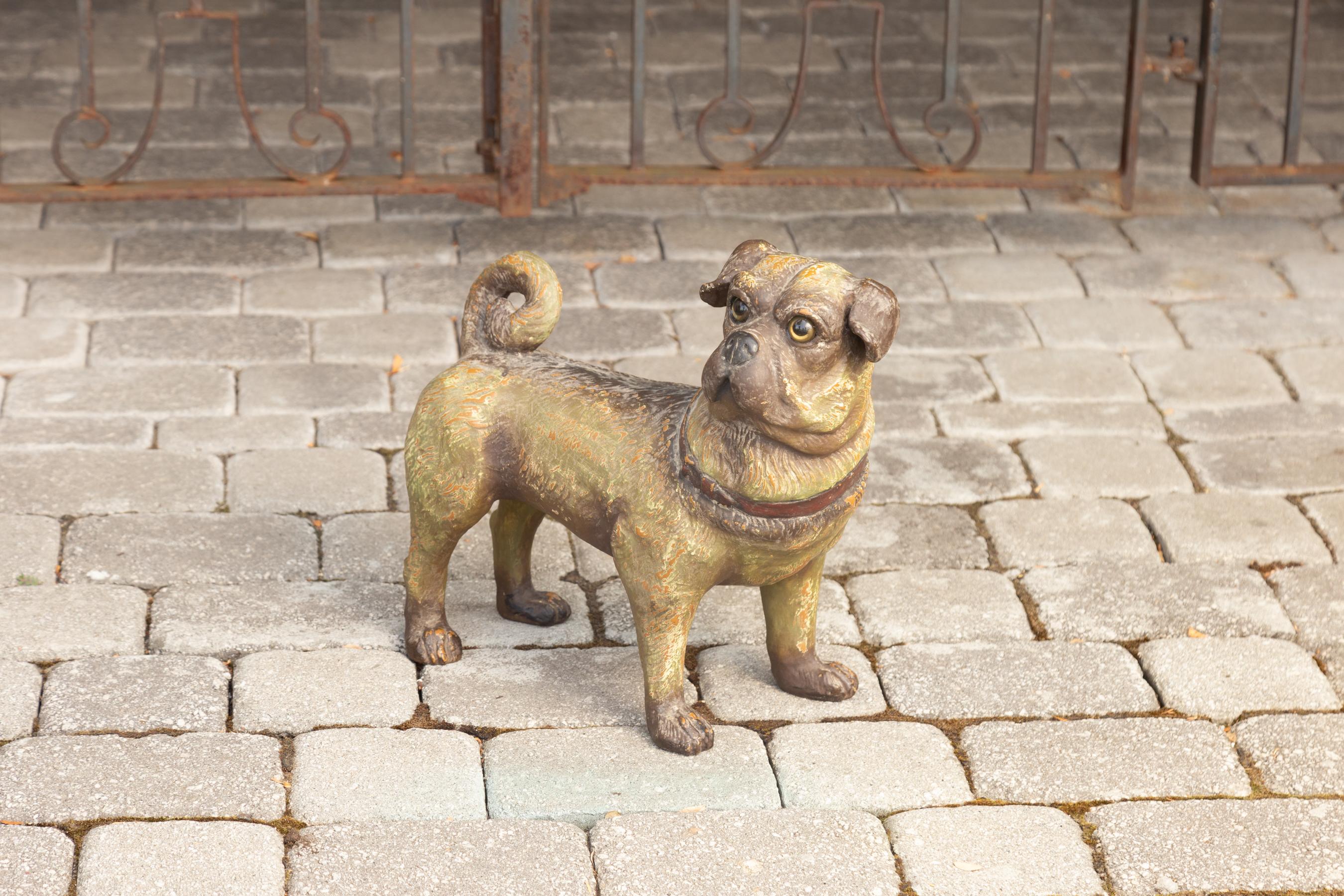A vintage English composition standing dog sculpture from the 20th century, with glass eyes and red collar. Crafted in England during the midcentury period, this dog sculpture features a pug standing proudly and firmly on his four paws, in an alert