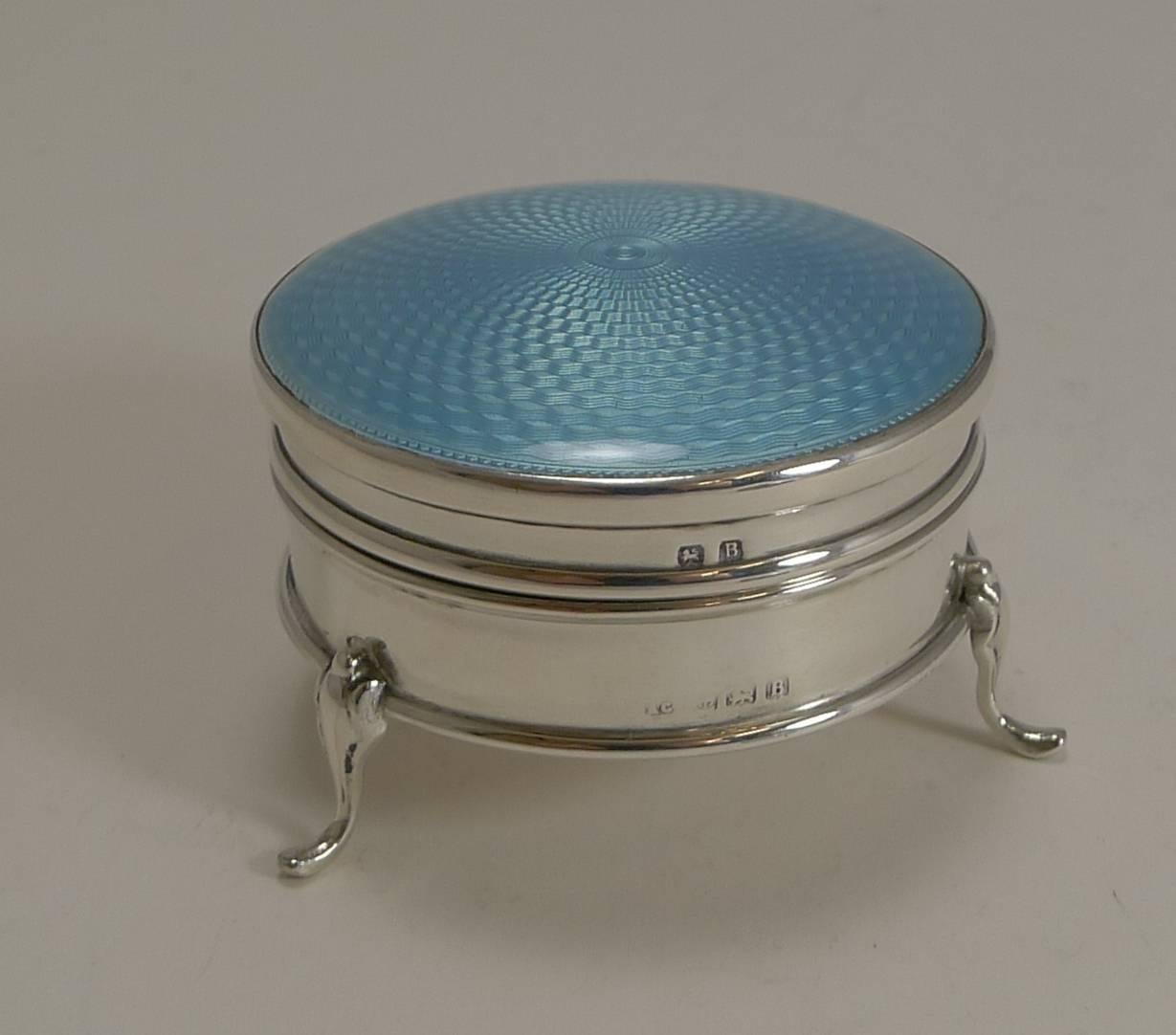 A pretty Art Deco box made from English sterling silver standing on three cabriole legs.

The hinged lid is domed and beautifully decorated with a pretty Aqua / Blue guilloche enamel, without damage. The patina is bright and showcases the