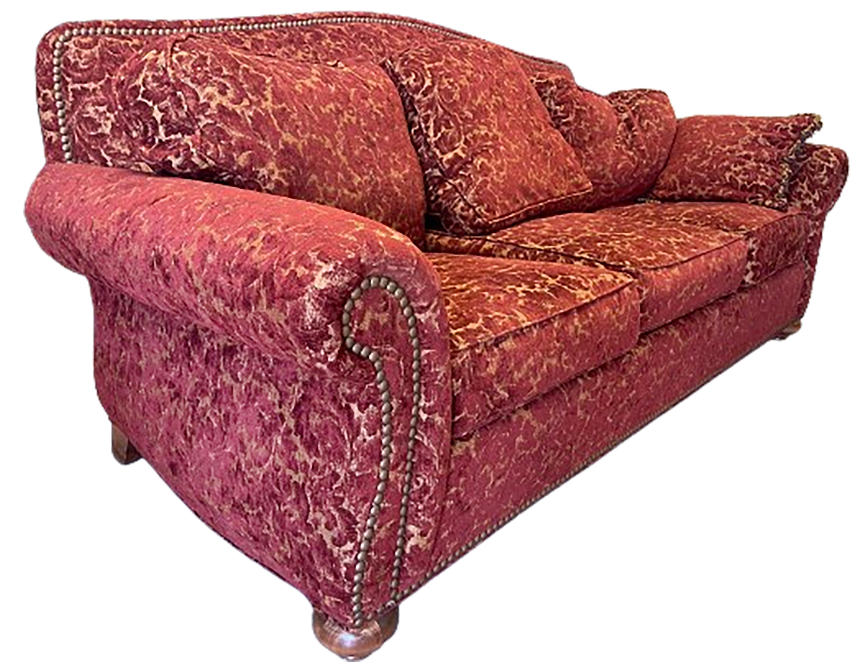 A charming vintage English floral pattern red loveseat with three cushions. Brass tacks line the bottom, back, top, and outer frame of the arms. Angled back for support and comfort.  Upholstered with rich cream and carmine chenille. 

No obvious