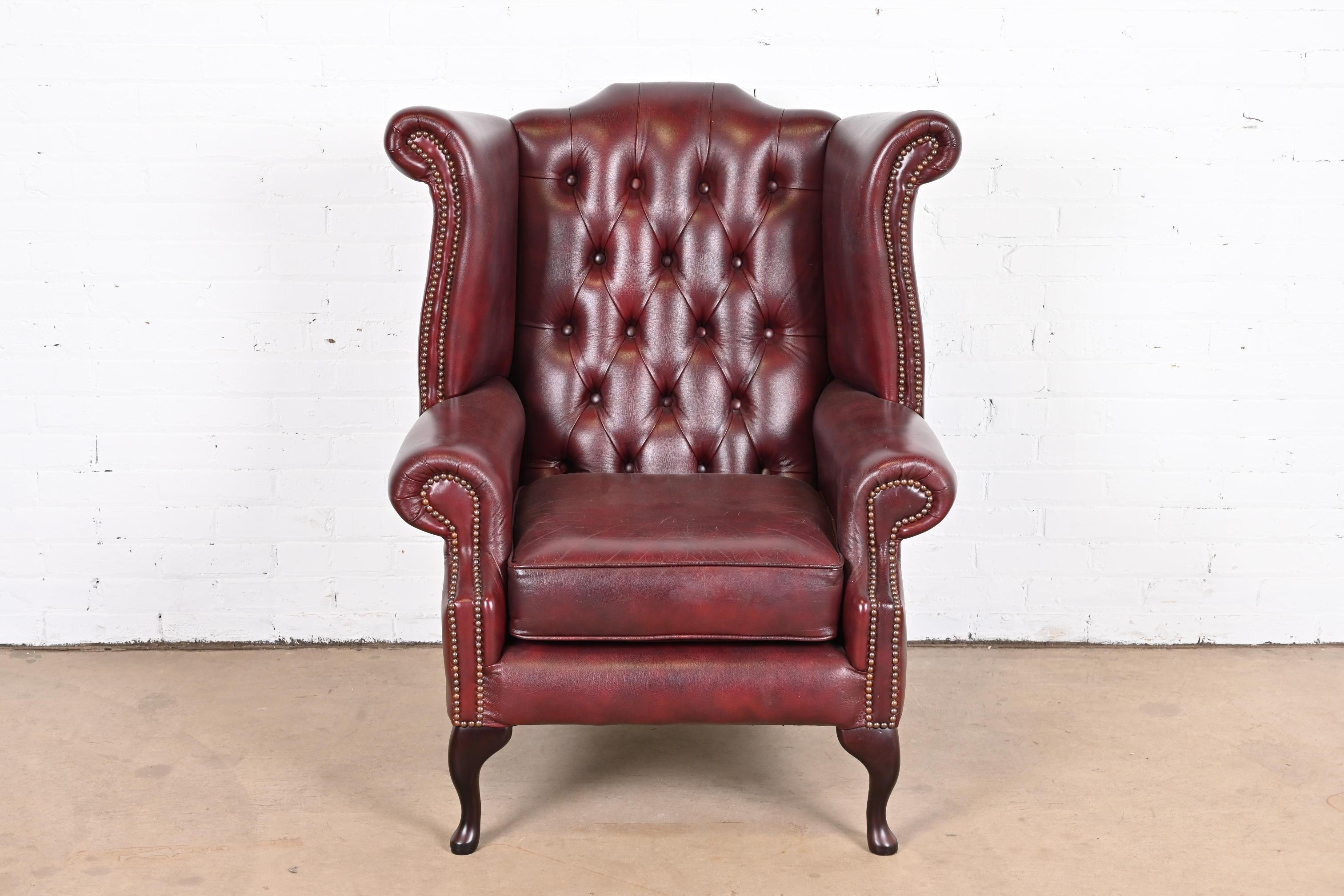 A gorgeous vintage Chesterfield wingback lounge chair

England, Circa Late 20th Century

Tufted oxblood leather, with brass studs and mahogany legs.

Measures: 35.5