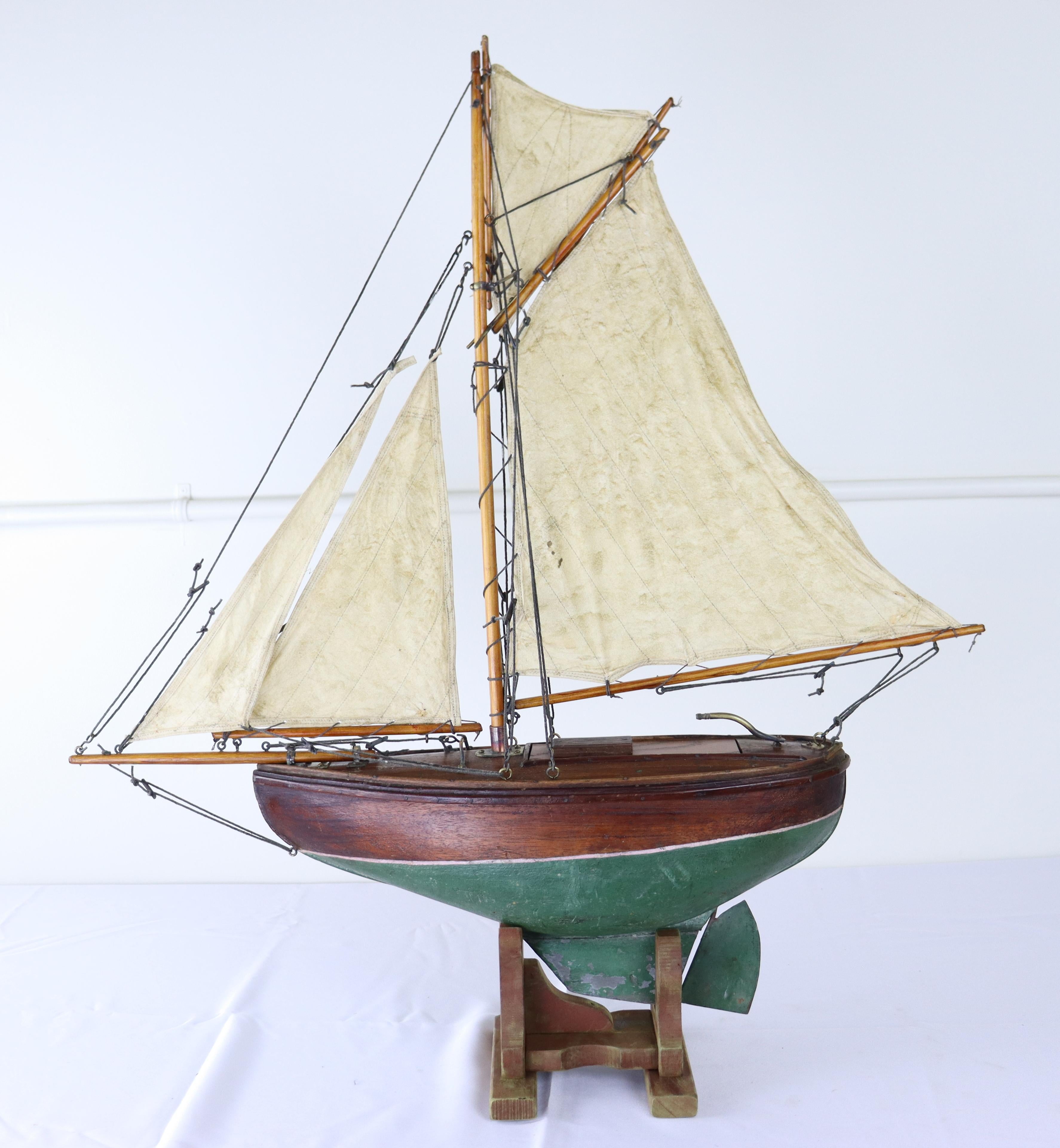 A charming vintage model yacht with sails made from old sail cloth and original brass accents. Stand is recent to hold the ship upright and stabile.  Measurements include the stand.  Heavier and more substantial than other pond yachts we have seen.