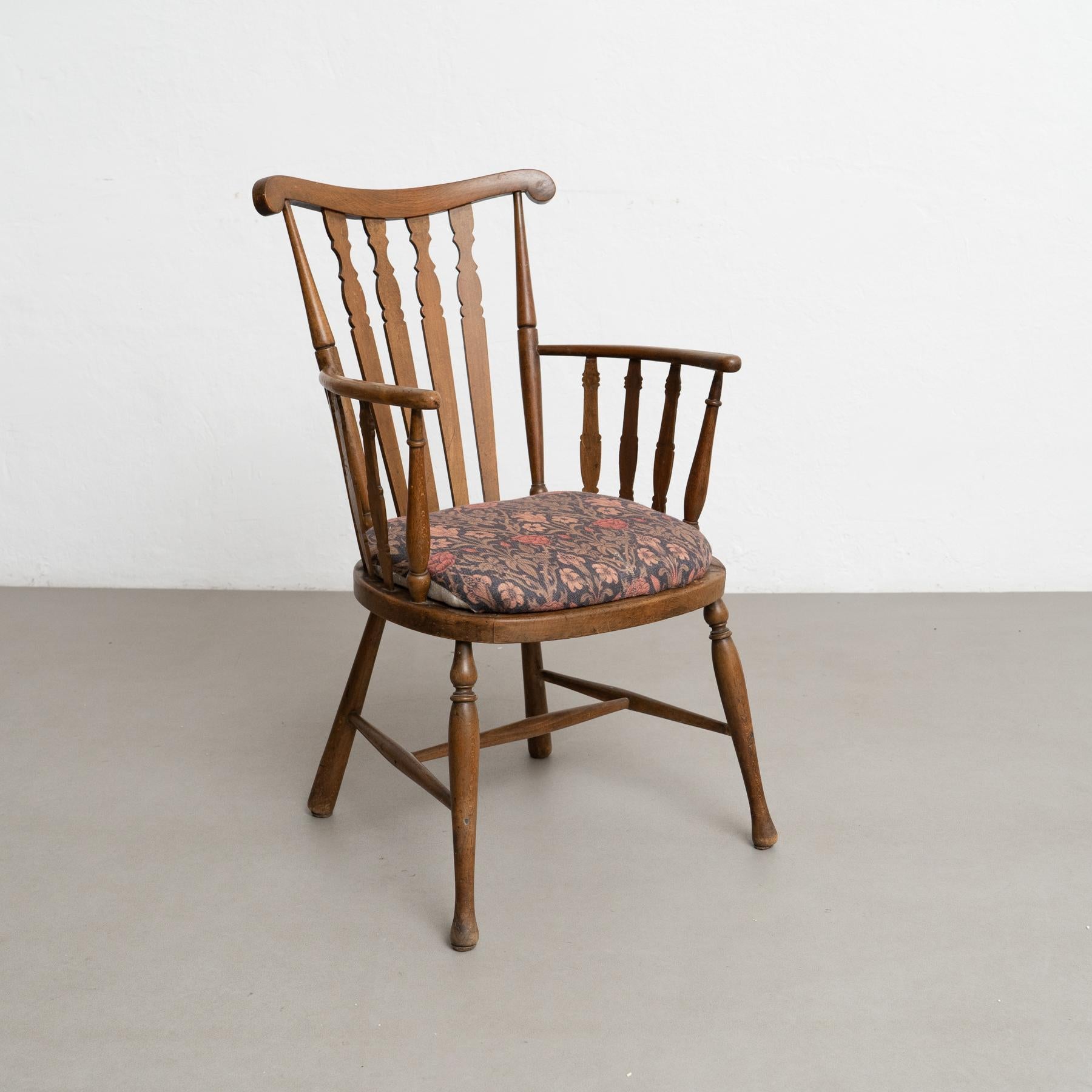 This elegant vintage English wood armchair, dating from circa 1950, showcases timeless craftsmanship and enduring style. Designed by an unknown artisan, the chair features a classic wooden frame with a beautifully aged patina that highlights its