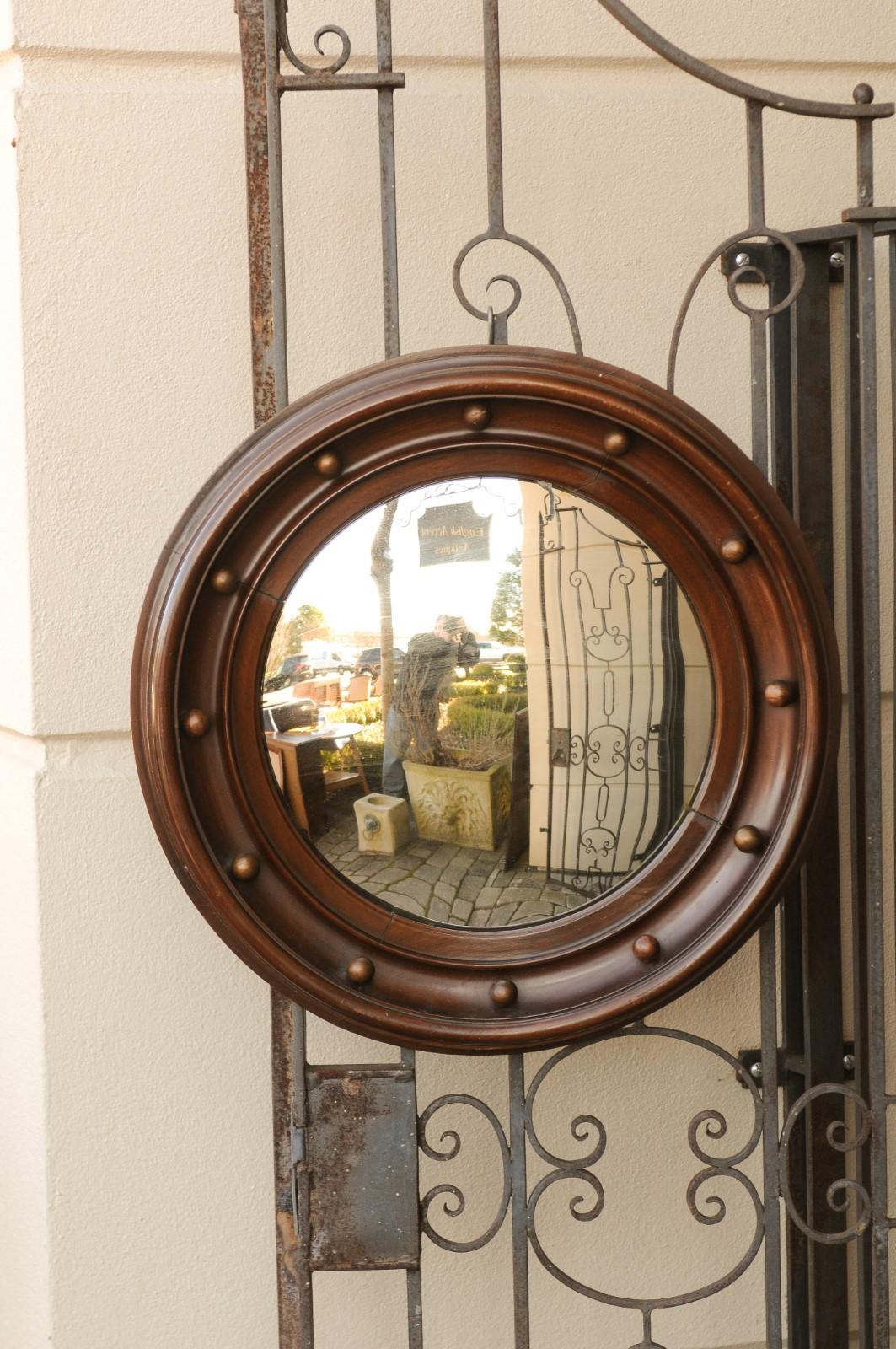 An English vintage wooden girandole bullseye convex mirror from the mid-20th century, with petite spheres. Born in England during the midcentury period, this handsome girandole mirror features a circular molded wooden frame, delicately accented with