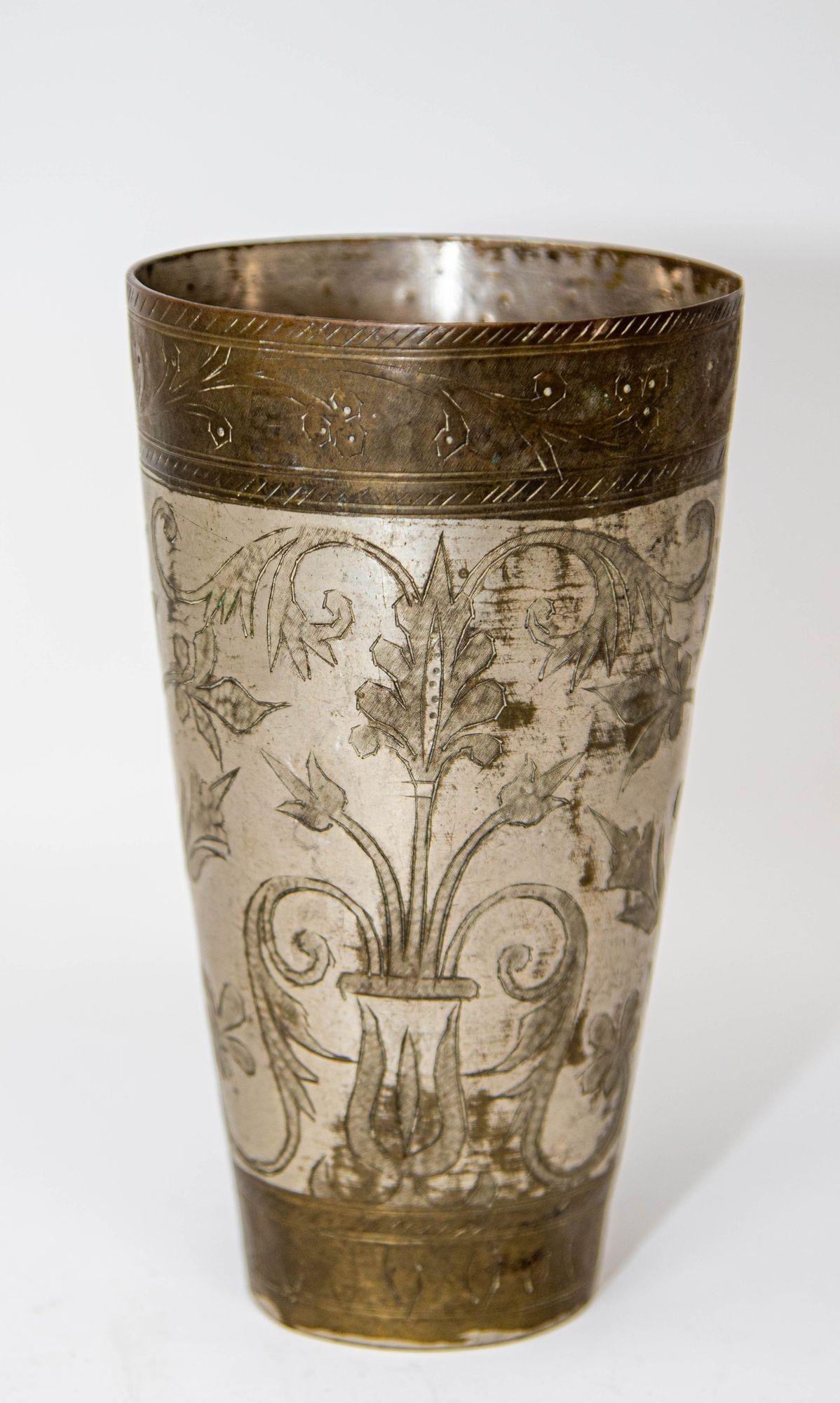 Vaso antiguo de metal plateado martillado y grabado, bellamente cincelado a mano y decorado con motivos geométricos y botánicos barrocos.
Taza de metal para beber lassi de estilo mogol islámico, única en su género, procedente de la India y