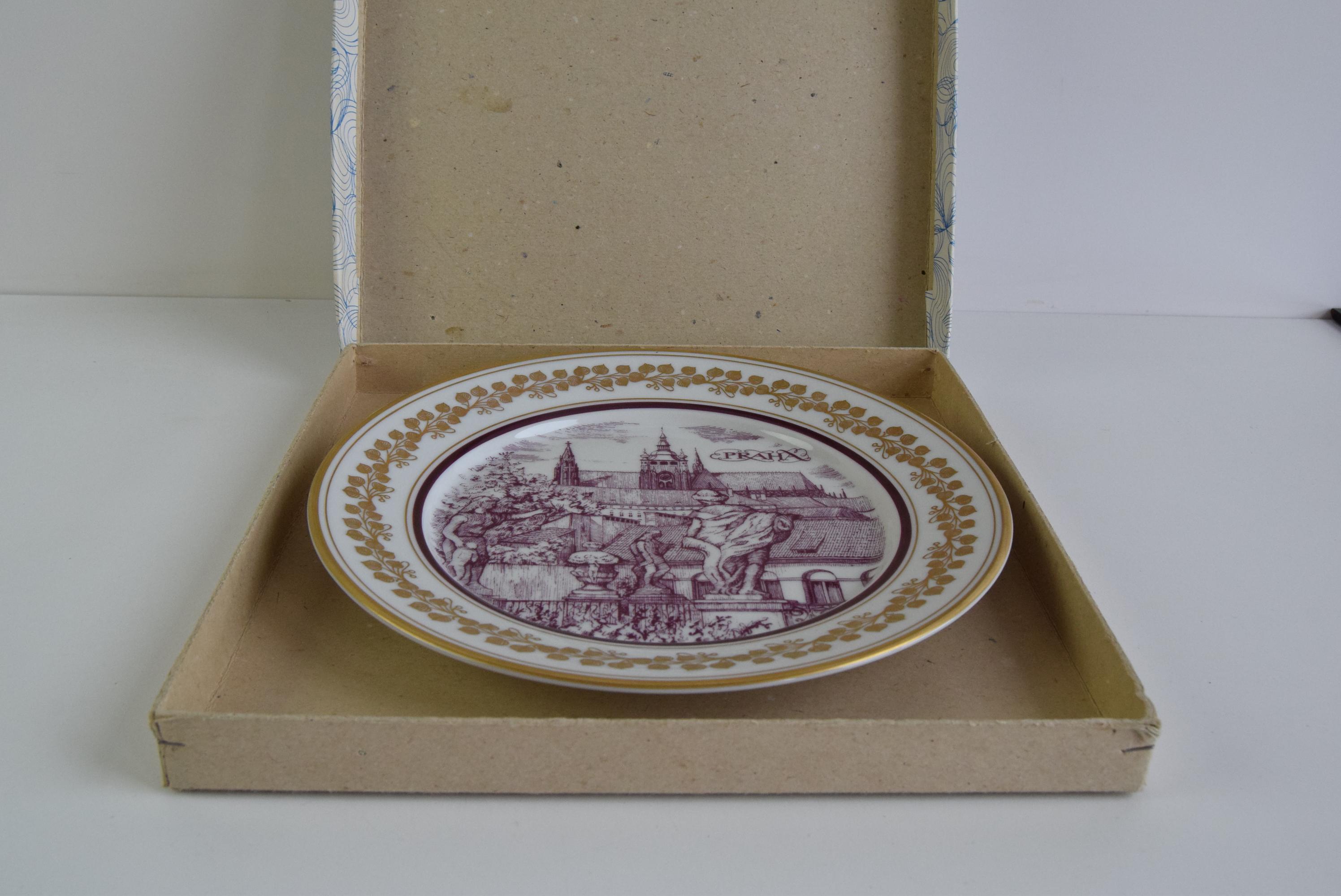 A beatiful vintage porcelain plate by Epiag Orion, featuring a detailed depiction od Prague. The central image shows CHarles Bridge and Prague Castle in a charming burgundy sepia tone, framed by a decorative golden border.
This peace is both a