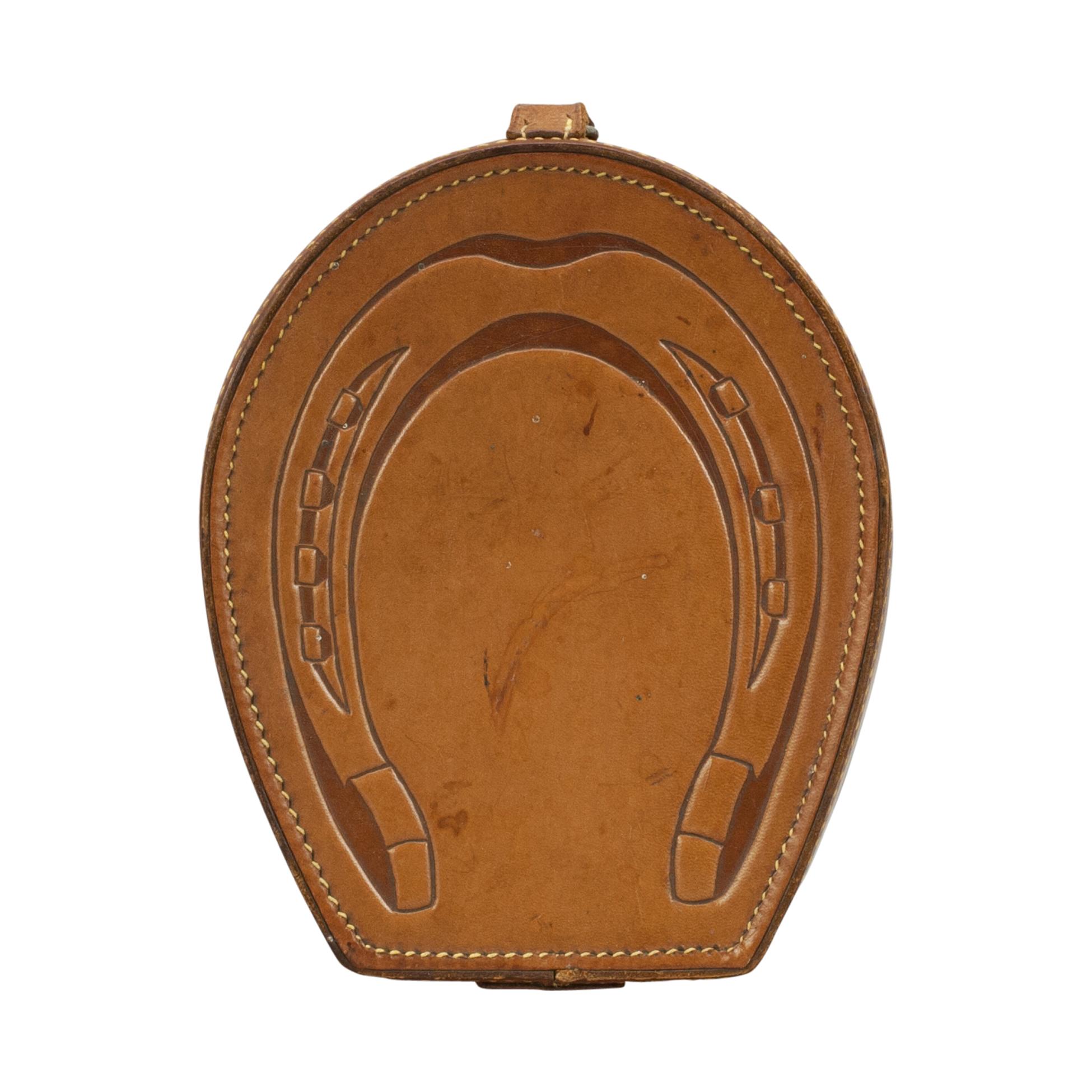 Vintage equestrian collar box.
Unusual leather collar box in the shape of a horseshoe. The lid embossed with a horseshoe complete with nailheads. The lid fastens with a leather buckle. A great vintage leather box with clean interior, ideal for