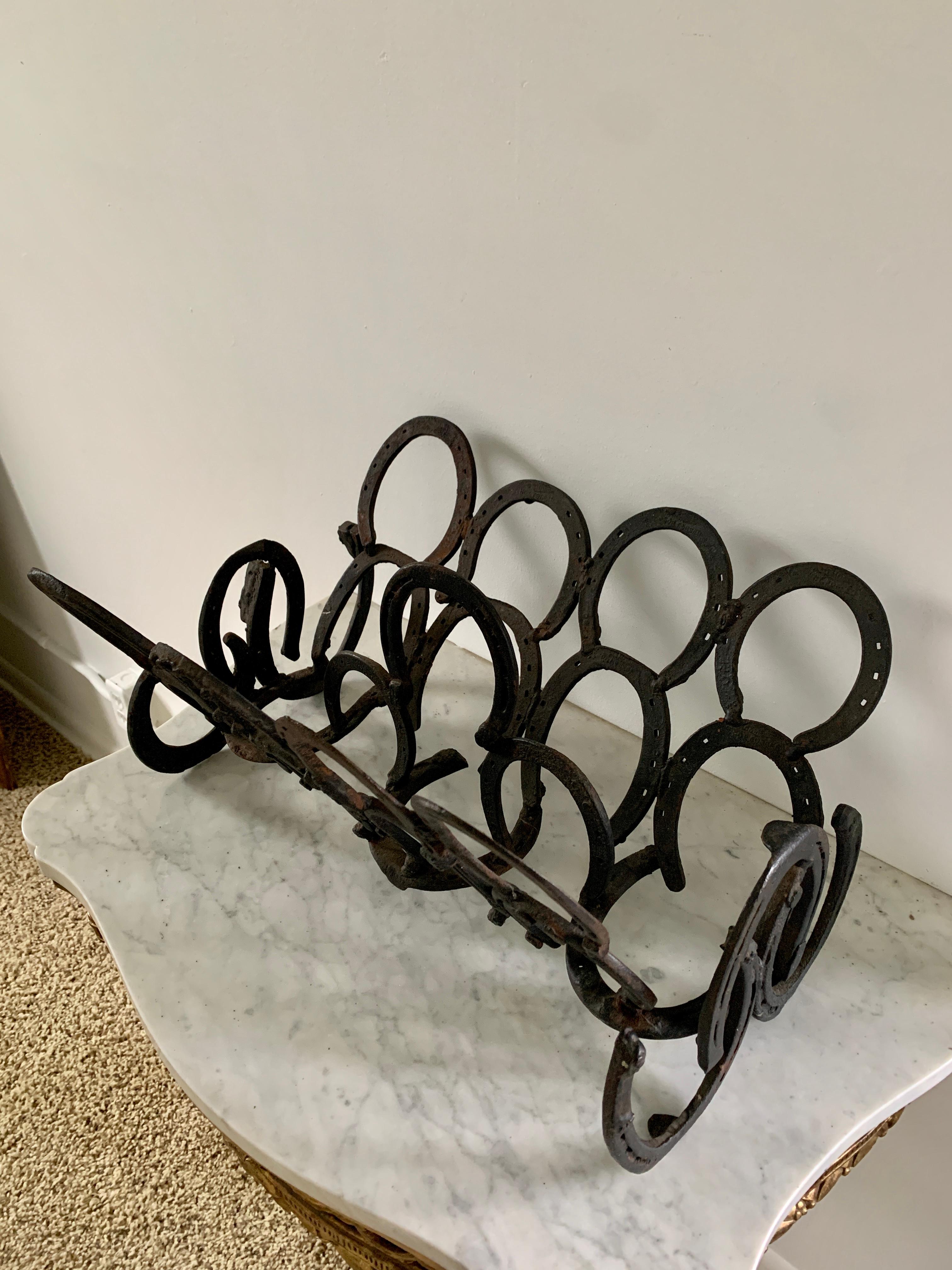 A stunning vintage hand-forged cast iron equestrian, farmhouse, or rustic horseshoe magazine rack or book stand

USA, Mid-20th Century

Measures: 20.25
