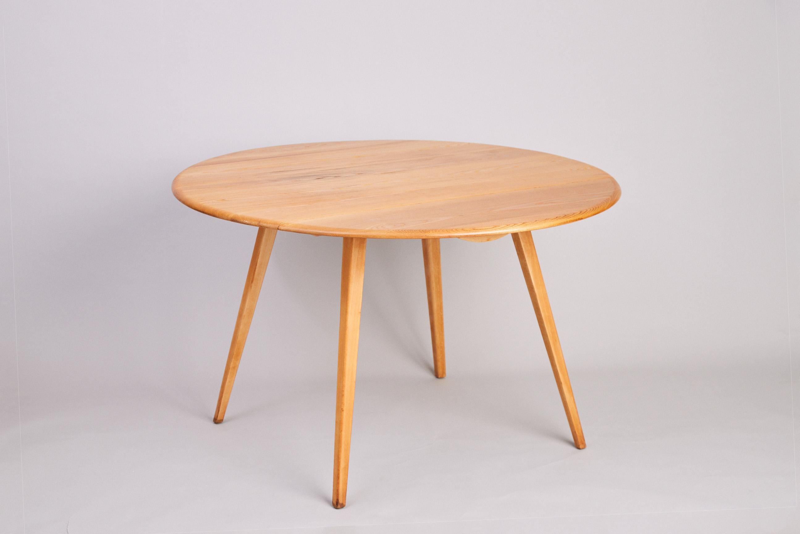 Vintage Ercol round drop leaf dining table (earlier blue label model). Referred to in Ercol's 1956 catalogue as model 384 and designed to sit 6 people when fully opened.
Solid elm top on beech legs. In the desirable blonde Elm, this item has been