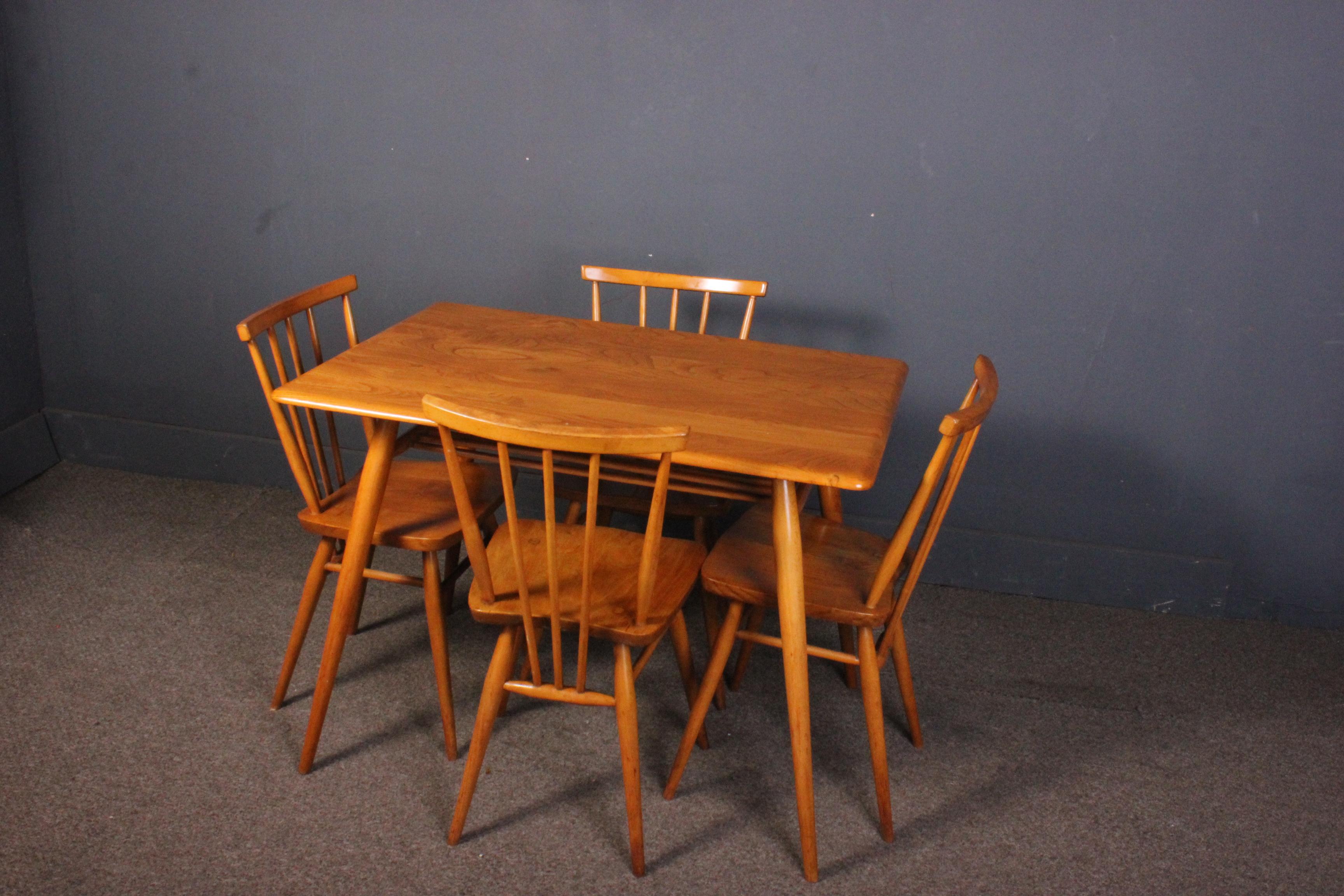 A beautiful vintage 1960s Ercol dining/breakfast table with magazine rack and 391 Ercol chairs x 4. The table and chairs feature an elm top and beech legs and are in very good original condition with only a few slight marks due to use.