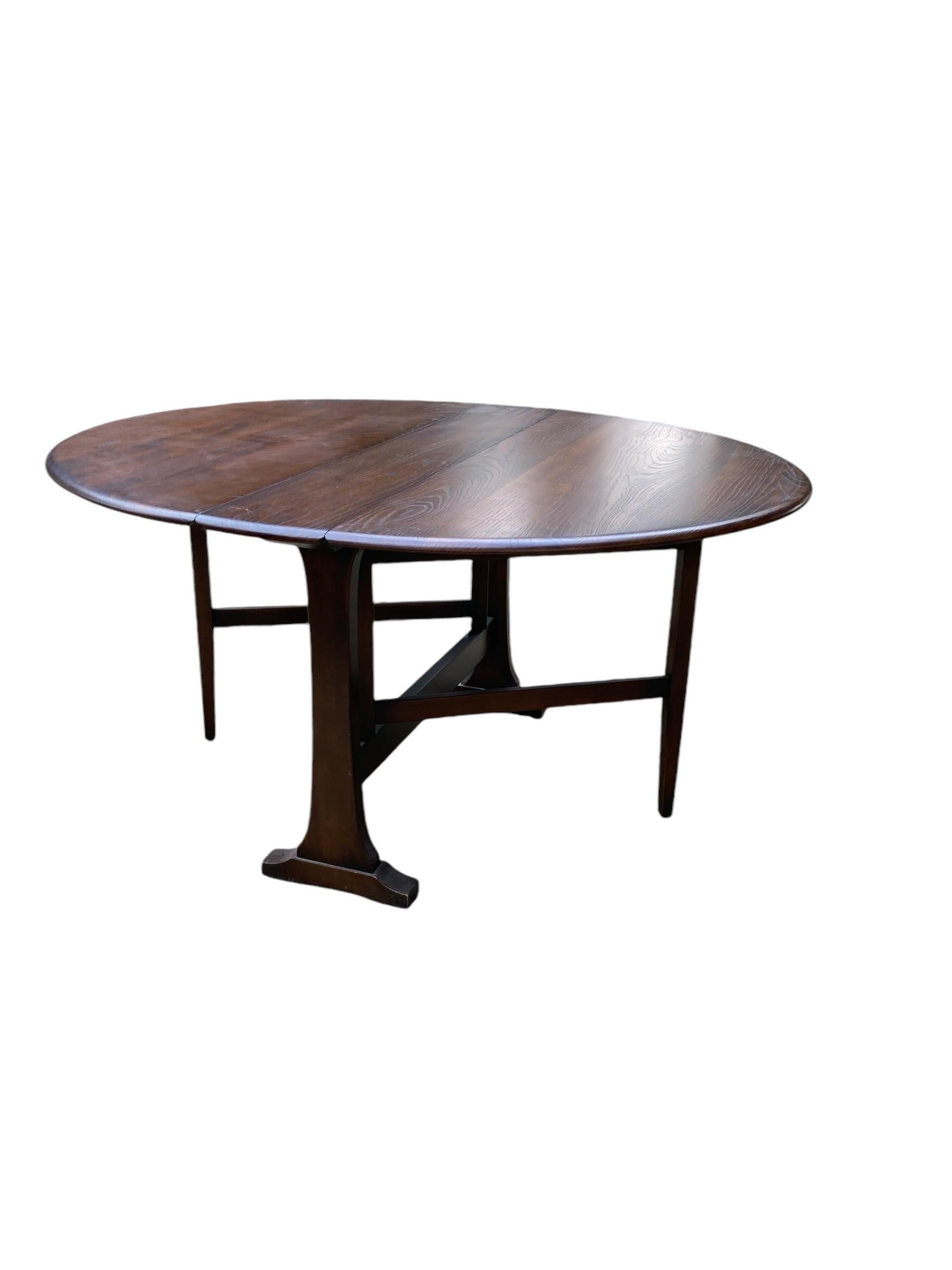 Table pliante Vintage Ercol Labellisée avec le tampon ERCOL d'origine. Finition en orme foncé. Très bon état, solide, des années 1960, Foldes pour un rangement pratique avec deux autres tailles pour deux, quatre ou six dîners.