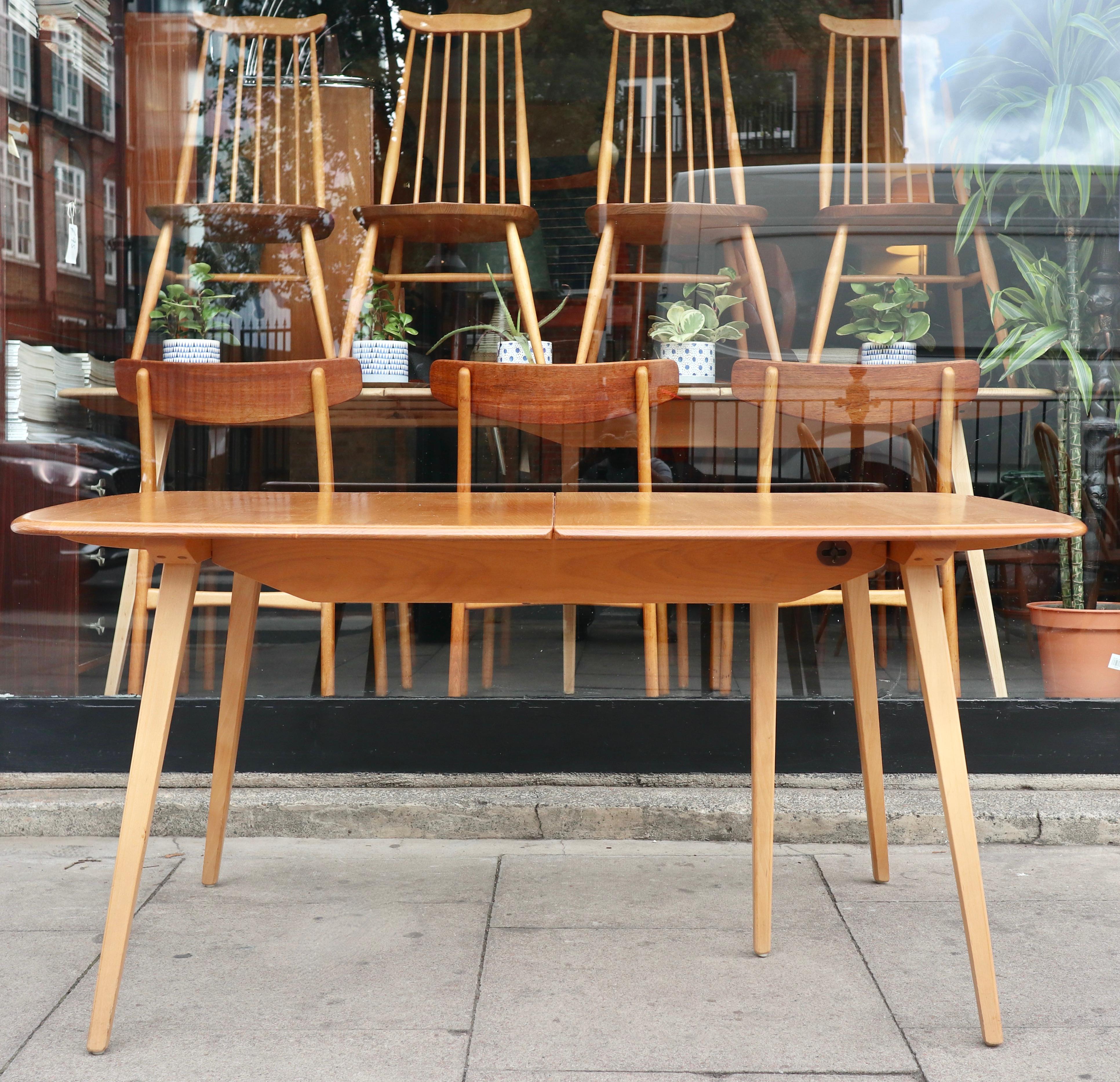 A stylish, refined and handsome vintage 1960s Ercol 'Grand Plank' windsor extending dining table.  This table has a solid Elmwood top resting upon solid Beech five legged base.  The table, when in an unextended position, is 152cm, however, when