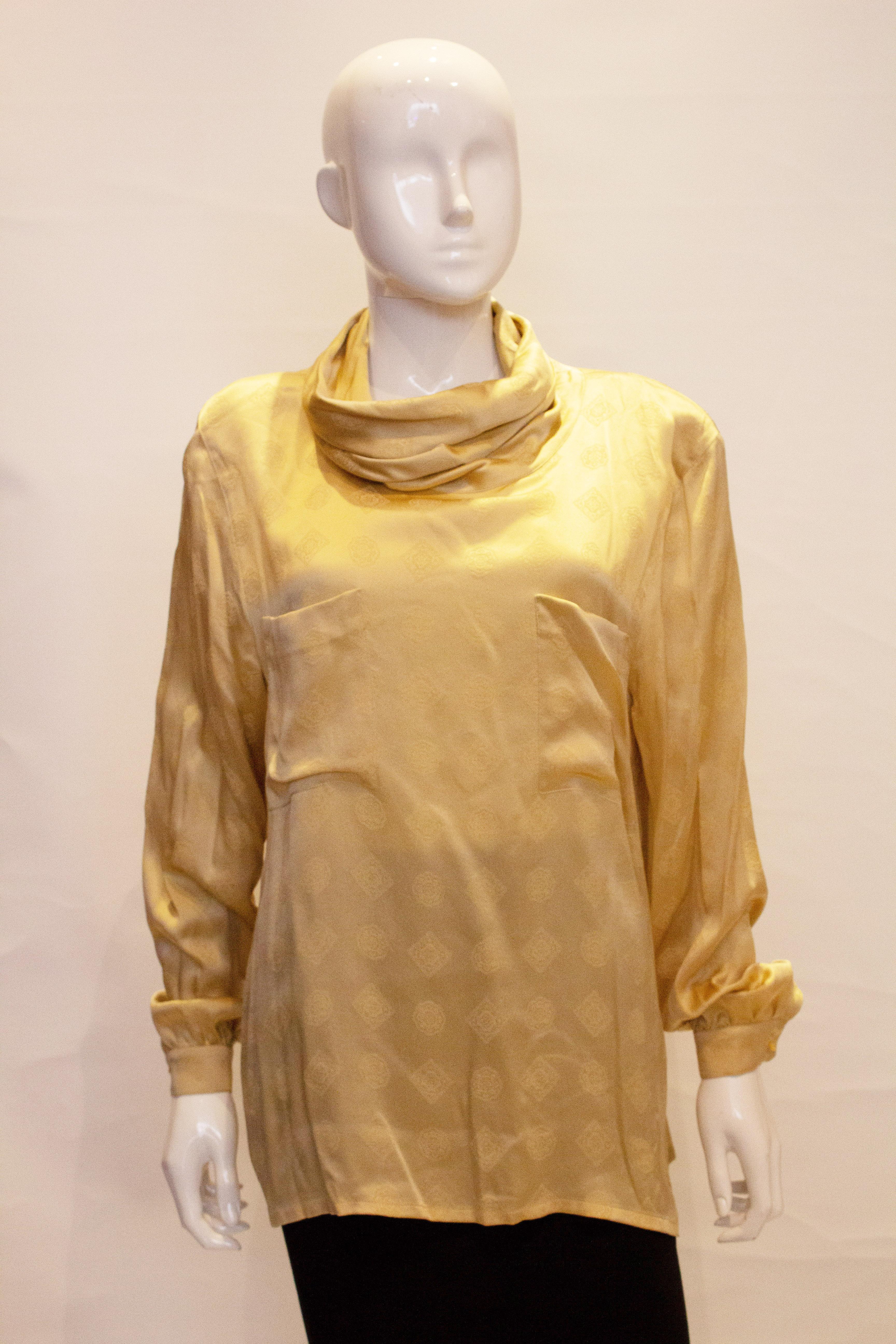 A great gold silk top by Escada.  The super soft silk has a woven pattern, and the top has two pockets on the front, a cowl like neckline and single button cuffs.