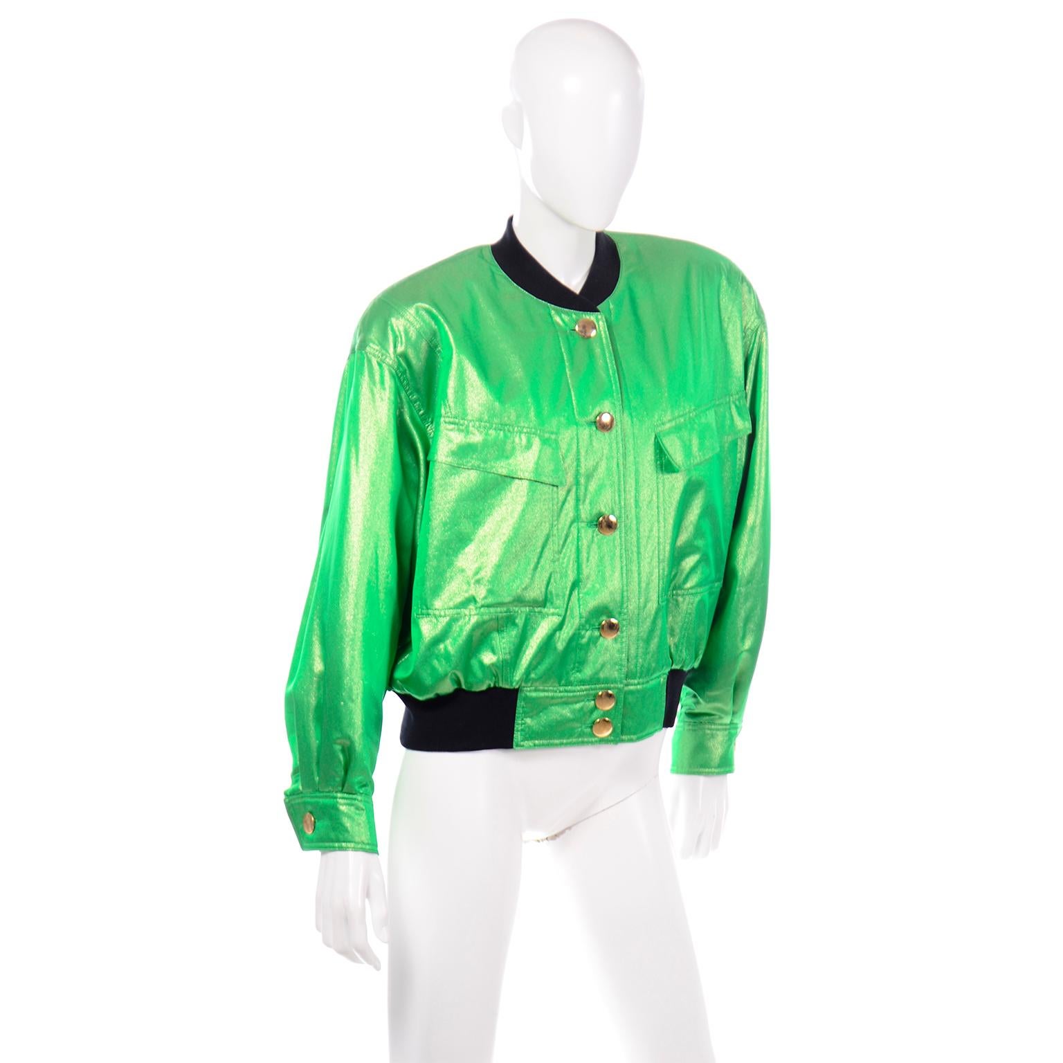This stunning, bold vintage Escada bomber jacket is in a green and gold iridescent silk and metallic fabric with gold tone hardware. The collar and hem of the jacket are lined with sweatshirt style black stretch knit.. The front of the jacket has