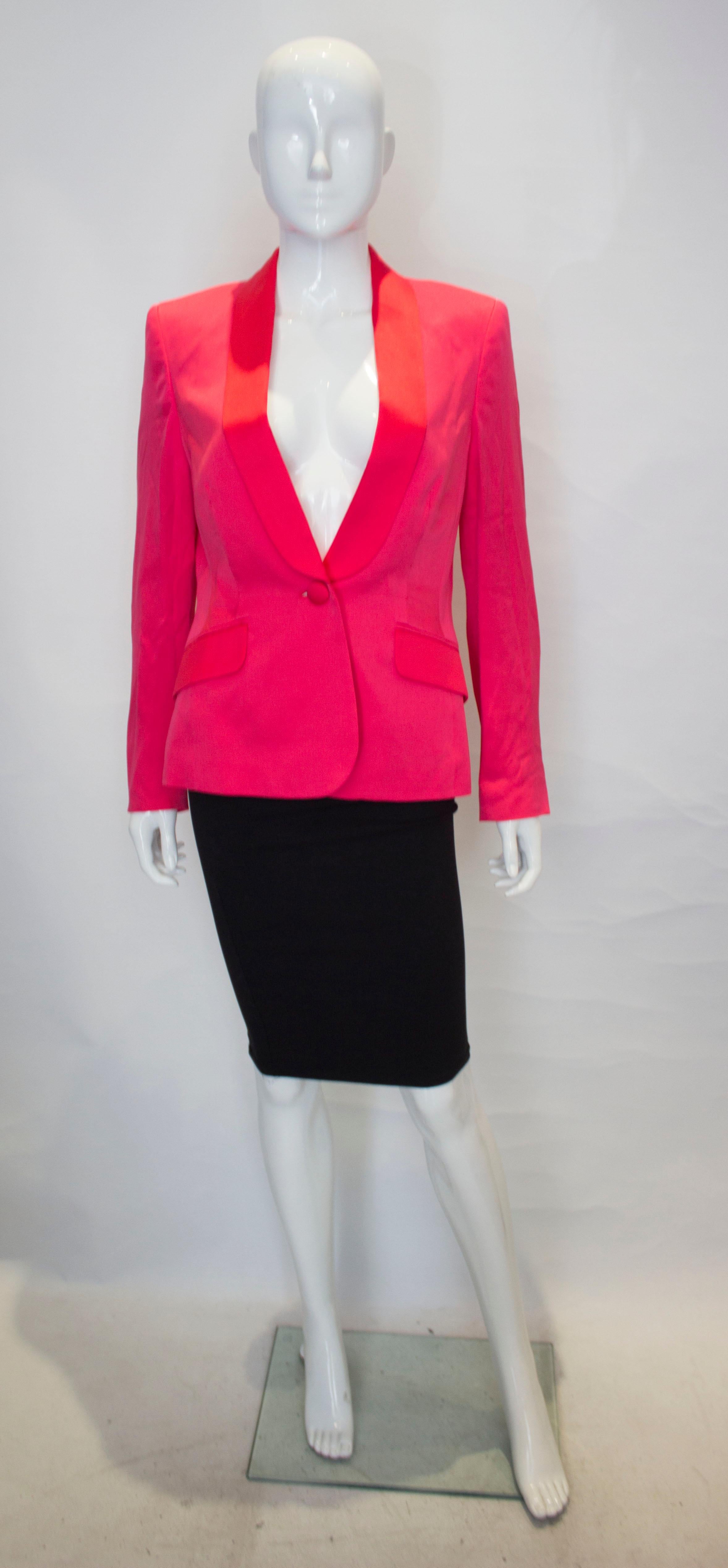 A subtle colour clash silk jacket by Escada. The jacket is in a red silk with a pink collar and pocket flaps.  It has a three covered button fastening and is fully lined.