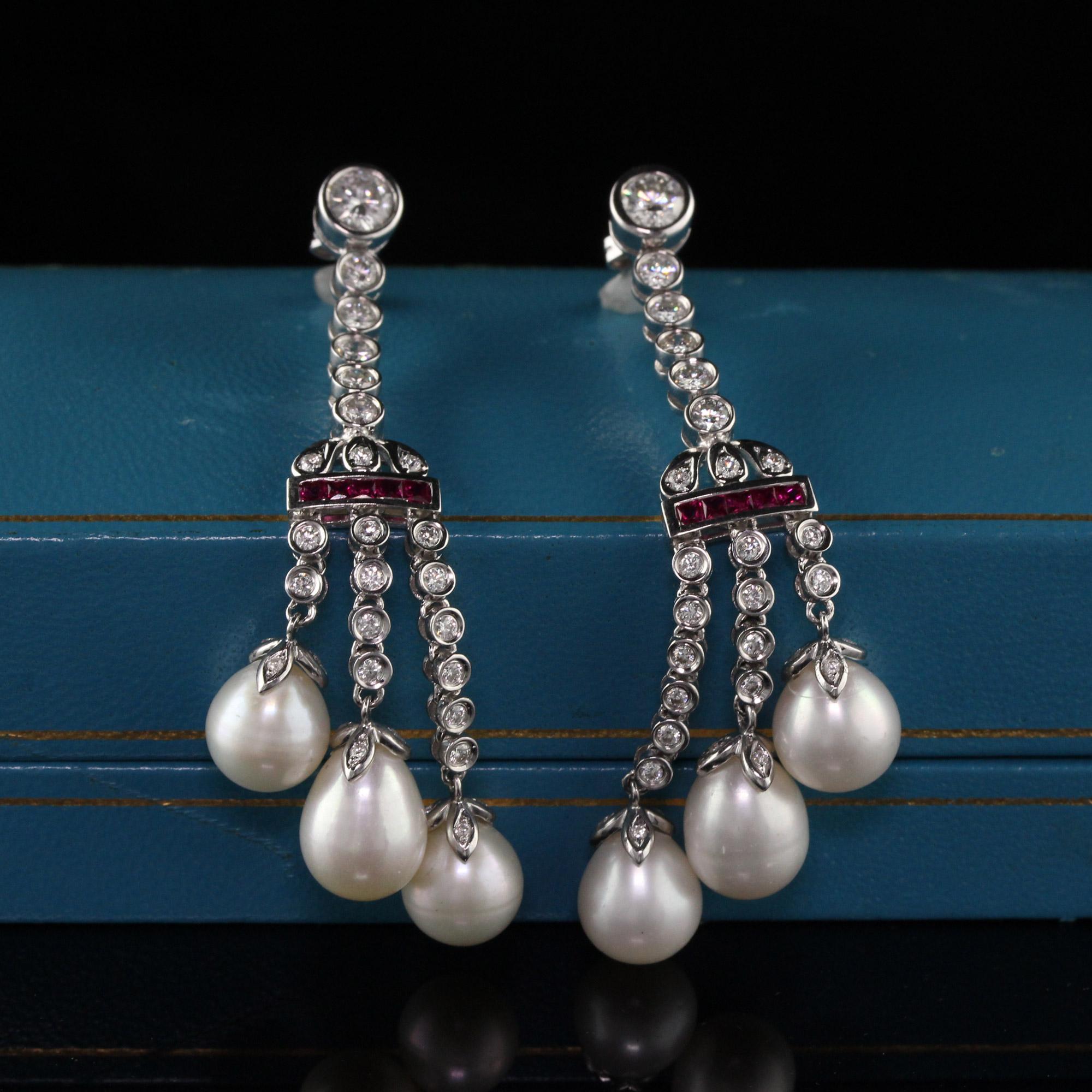 Dazzling diamond and ruby drop earrings with three dangling cultured pearls.

Metal: 18K White Gold

Weight: 17.5 Grams

Diamond Weight: Approx. 2 ct.

Diamond Color: H

Diamond Clarity: VS2

Gemstone Weight: Approx. 0.30 ct. ruby

Pearl