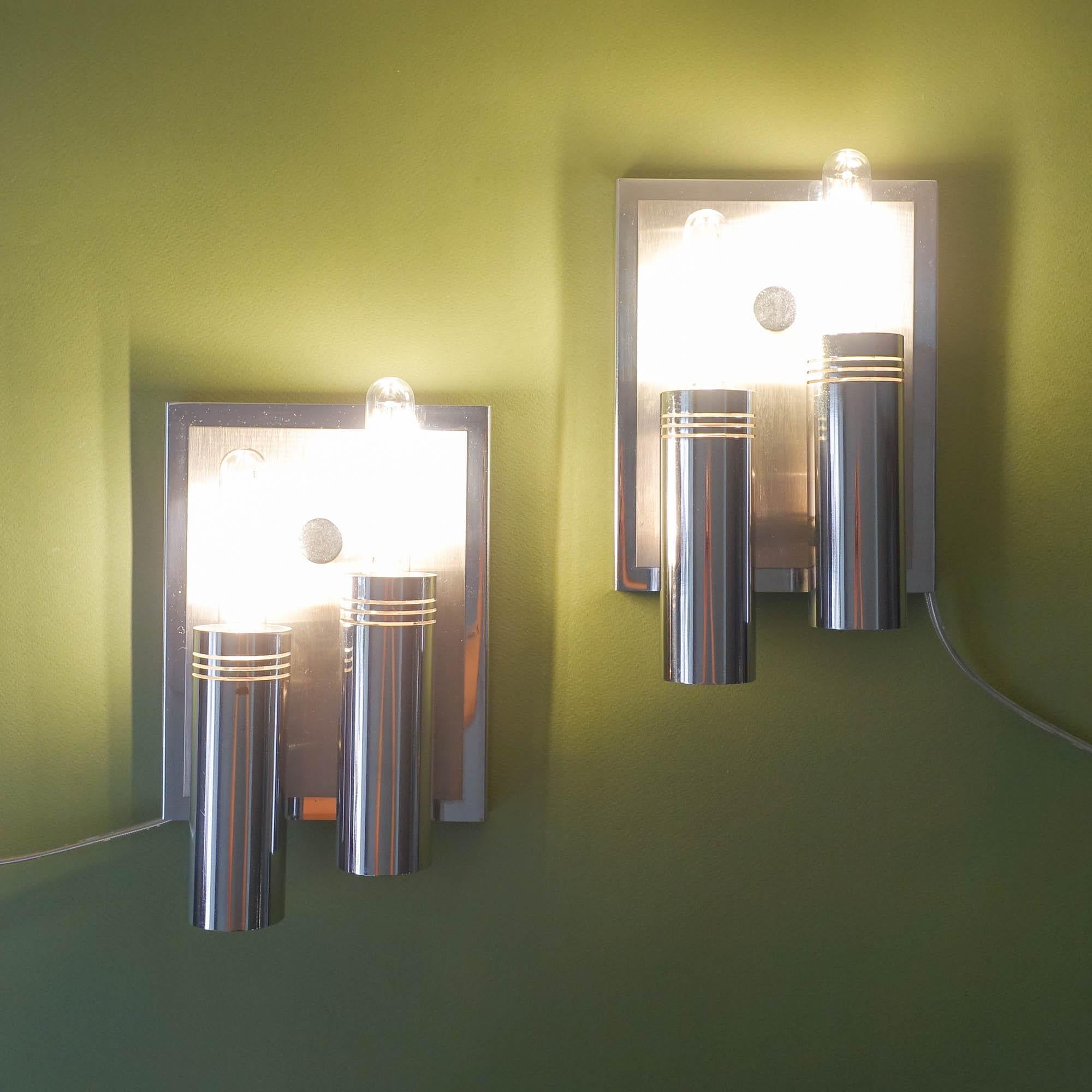 This pair of sconces was designed and produced by Estiluz, in Spain, during the 1970's. Each lamp features 2 parallel tubes, that are set on a rectangular plate with two metal finishes, one in chrome and the other brushed metal. In each tube fits 1