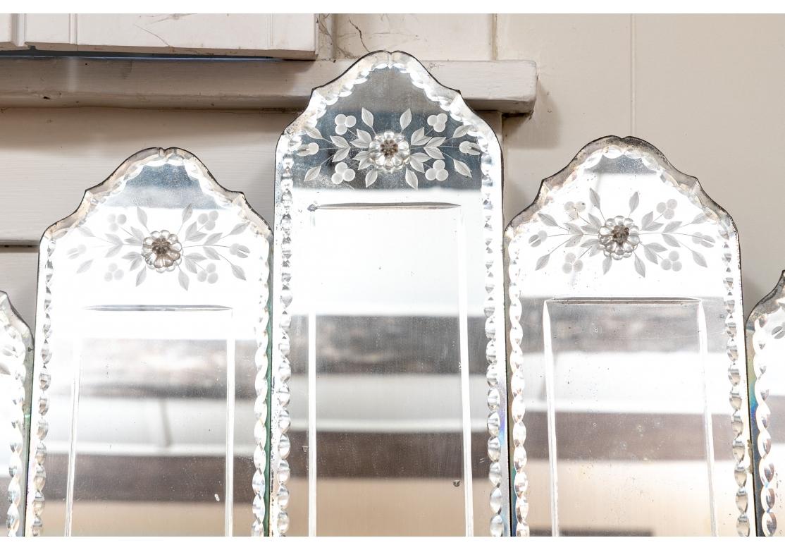 Intricate and spectacular etched mirror with a sectioned and graduated bridge-like design. Each section with bevel cut edges, etched floral designs, accentuated by crystal rosettes and three silver-tone floral medallions along the bottom. Wood