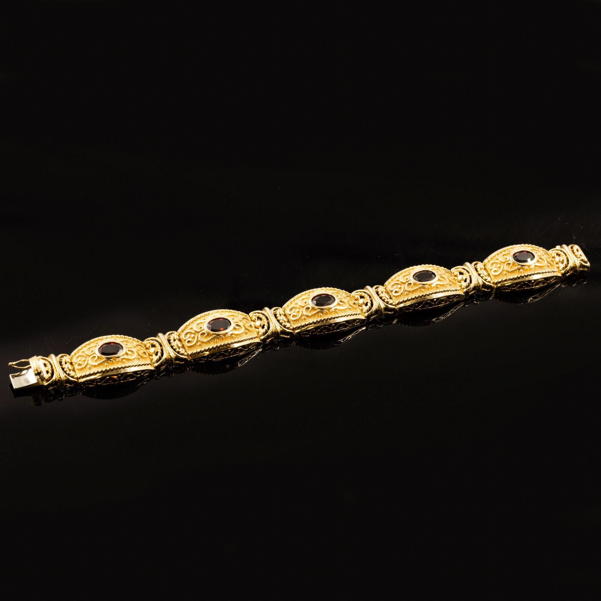 VINTAGE ETRUSCAN REVIVAL STYLE 14K GOLD AND GEMSTONE BRACELET
Item # 308QAJ11Z 

A very finely made bracelet in the Etruscan Revival taste, it is executed in solid 14k gold with five bezel-set garnets surrounded by bas-relief scrolling vines over a