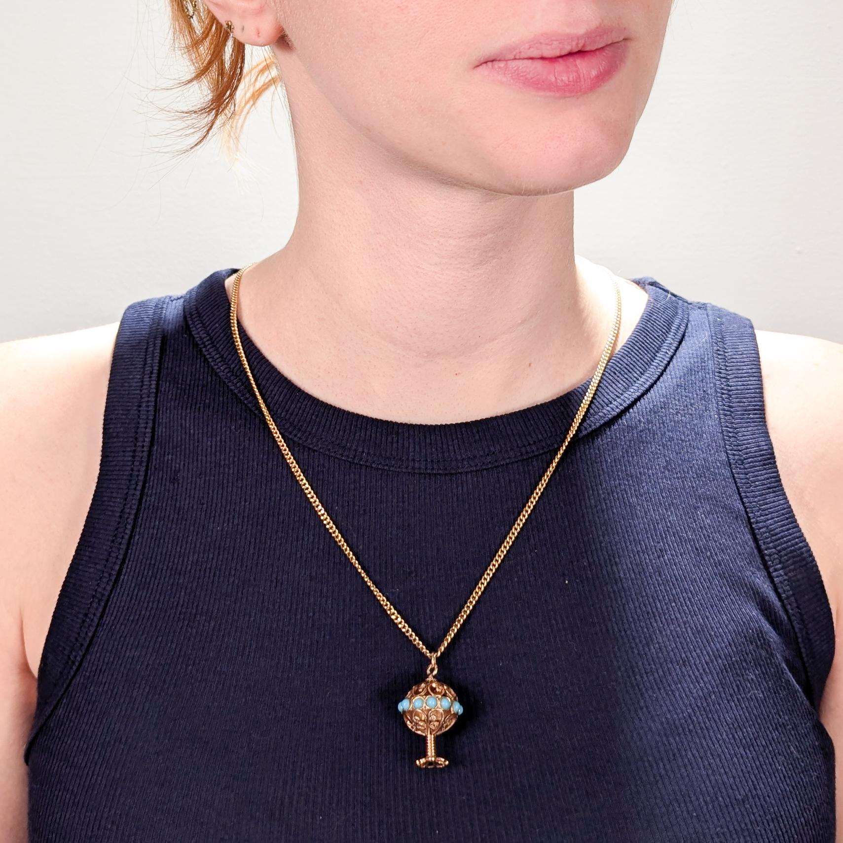 A very fine gold Etruscan Revival pendant charm.

In 18k yellow gold.

In the form of a hollow sphere with filigree flower petal sections and smooth round turquoise cabochons set around a center sphere that is supported by a gold coil pedestal and