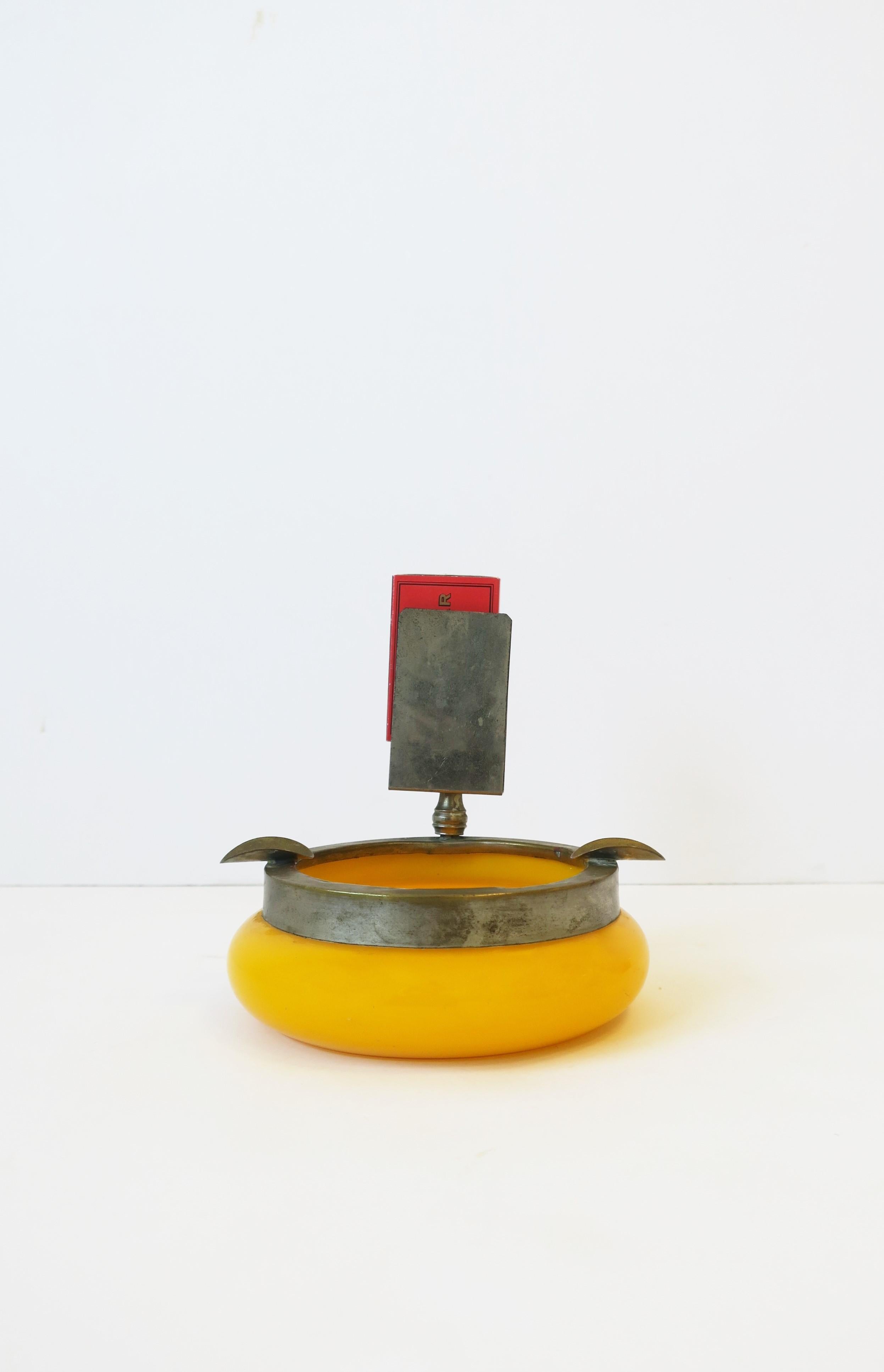 A yellow-orange art glass ashtray with protective metal edge, cigarette supports and matchbox holder area, circa early to mid-20th century, Slovenia. 

Dimensions: 4.75