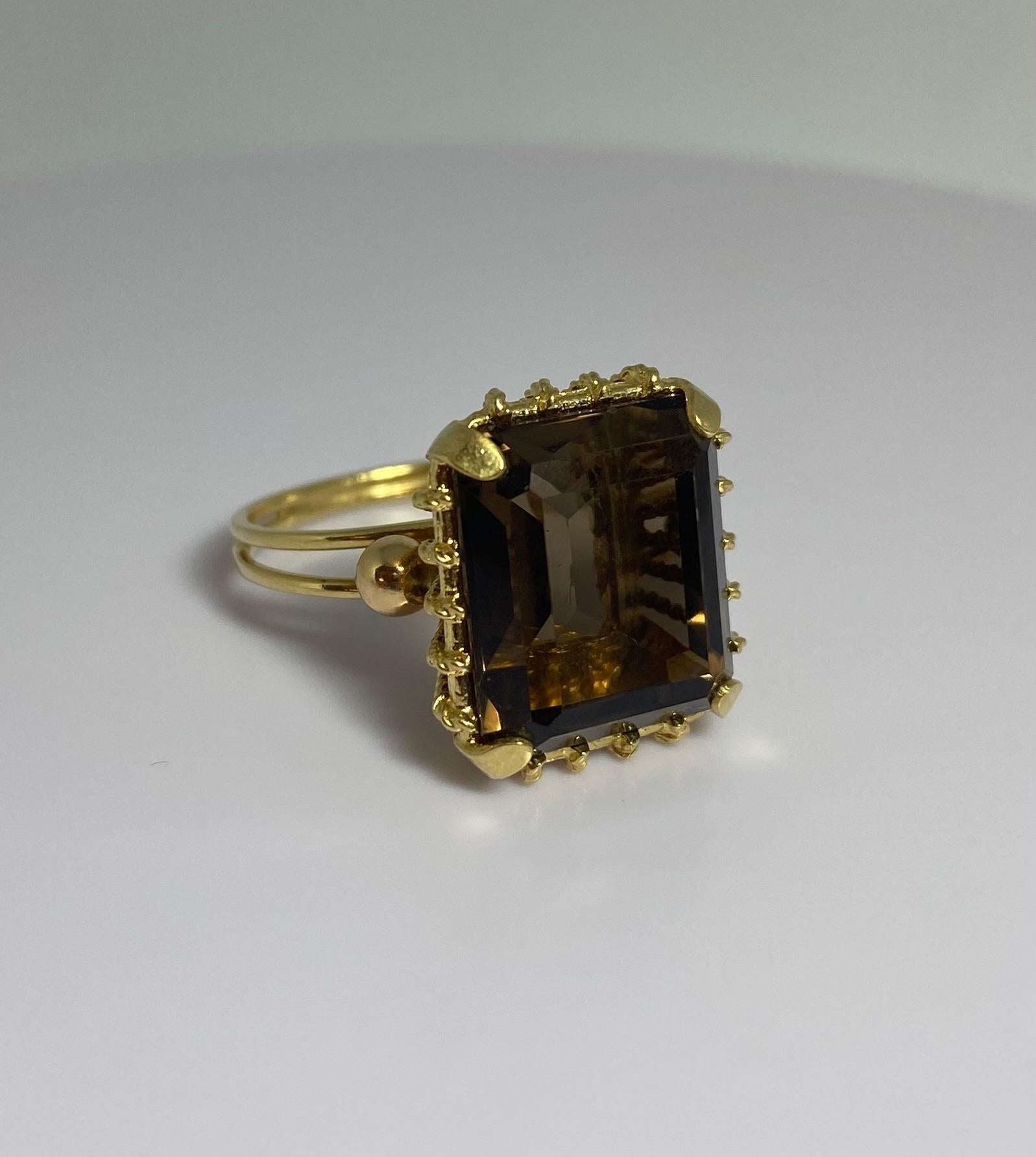 Step into the elegance of the 1950s with this gorgeous vintage cocktail ring, featuring a striking baguette-cut smoky quartz set in 18K yellow gold. The unique design of this Dutch-origin piece combines classic sophistication with a touch of vintage