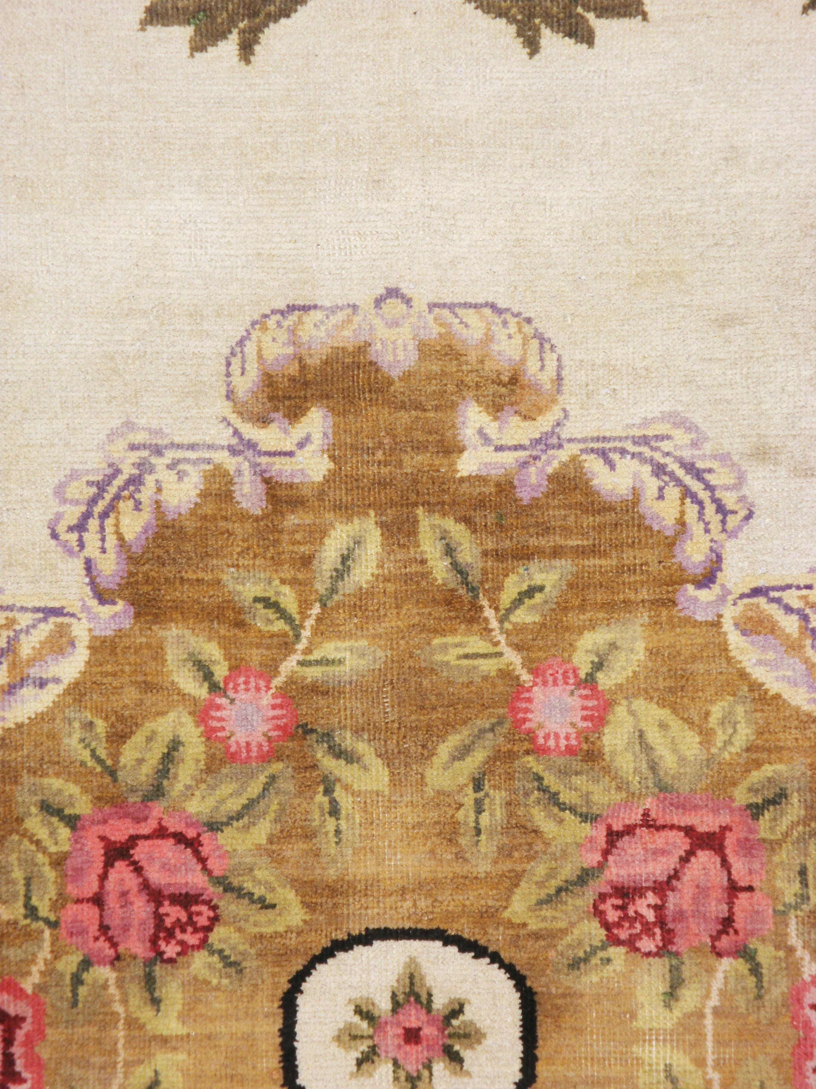 A vintage European continental carpet from the mid-20th century. A large golden brown medallion of roses populates the ivory field. A brown border is edged off by acanthus scroll leaves in shades of green.