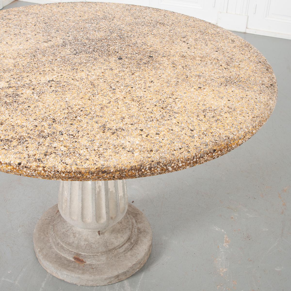 This is a lovely vintage European garden table. It has a pedestal base which has been cast with reconstituted stone. The round top has been cast in reconstituted stone with more small pebbles in its design. It would be a very attractive table for