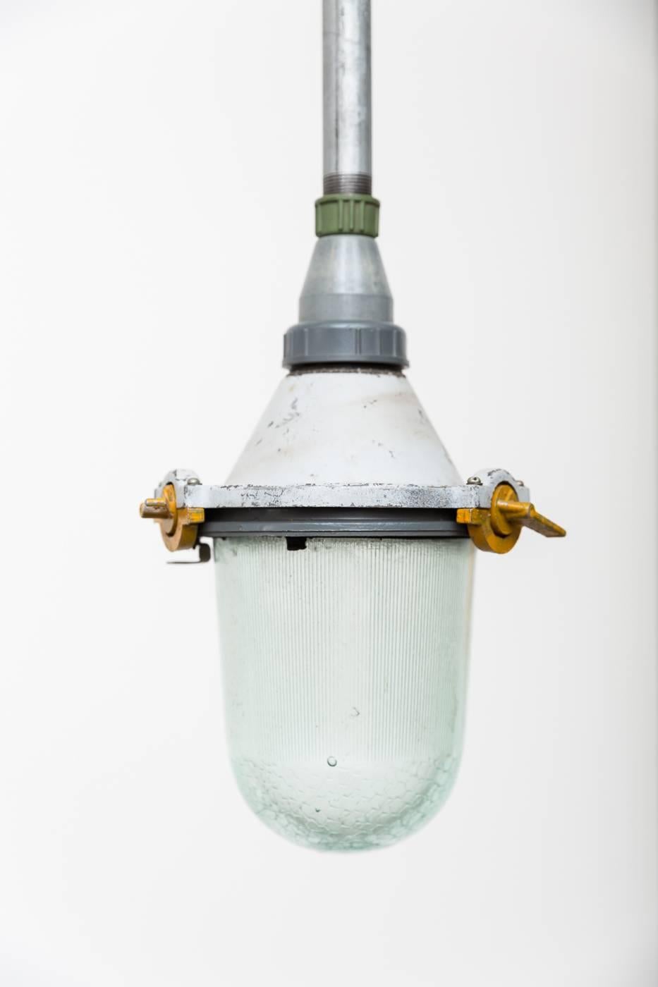 Amazing! Vintage industrial hanging factory lamps with enameled metal casing, glass shades and new steel pipe stems. In original condition, varying colors. 