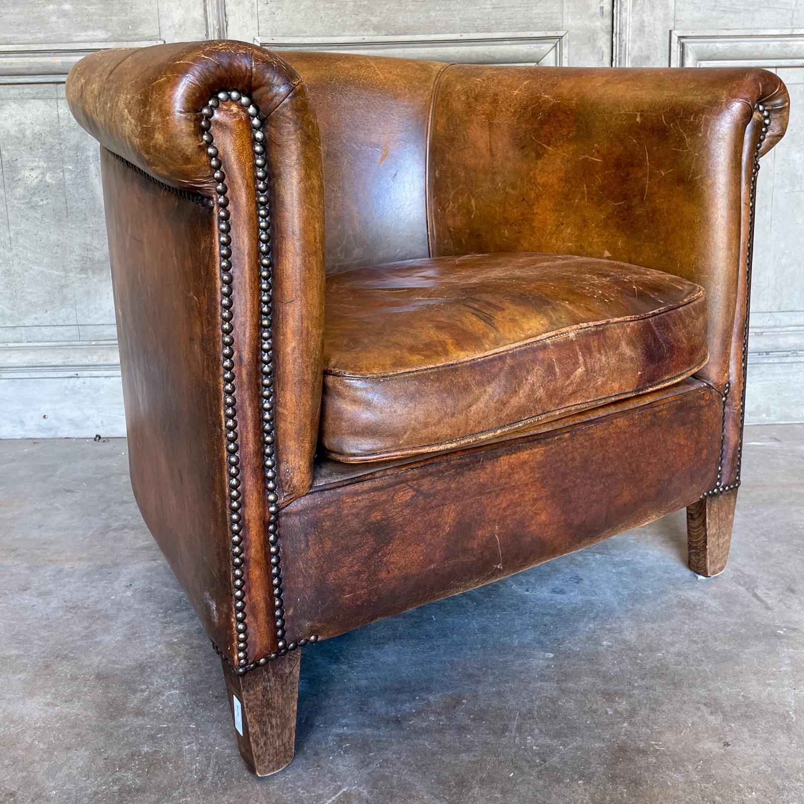 Cette chaise de baignoire en cuir européen vintage est dotée d'un cuir richement patiné et d'une tête de clou en laiton. Les pieds sont en bois et légèrement effilés. Le style du dossier en forme de tonneau de ce fauteuil est parfait pour flotter