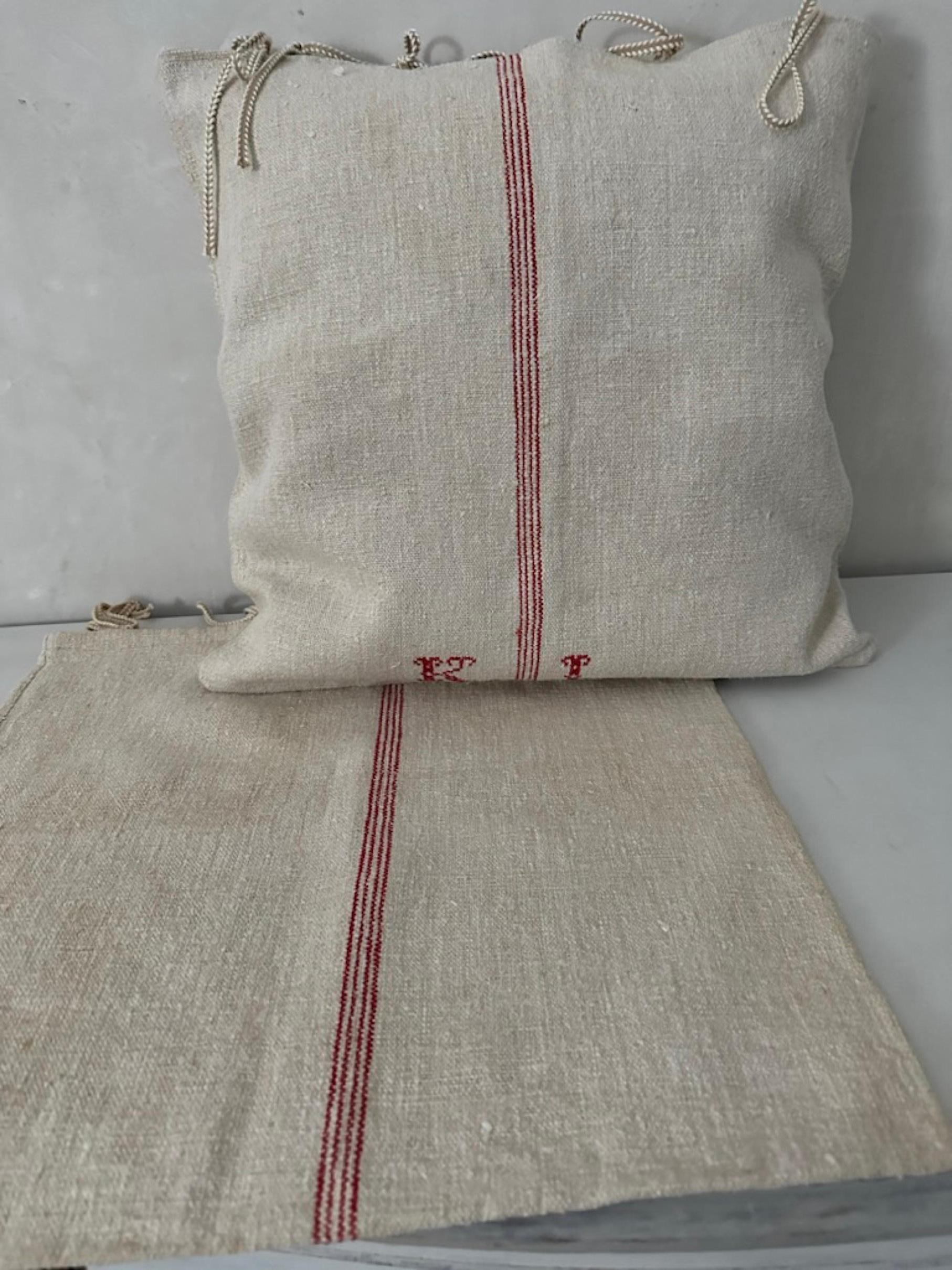 A single heavy weight grain feed sack from Europe has been made into two pillow cases with tassel closure. The woven hemp has monograms and center striping woven into the sack. 
Only one pillow has the monogram, the second with center stripes on