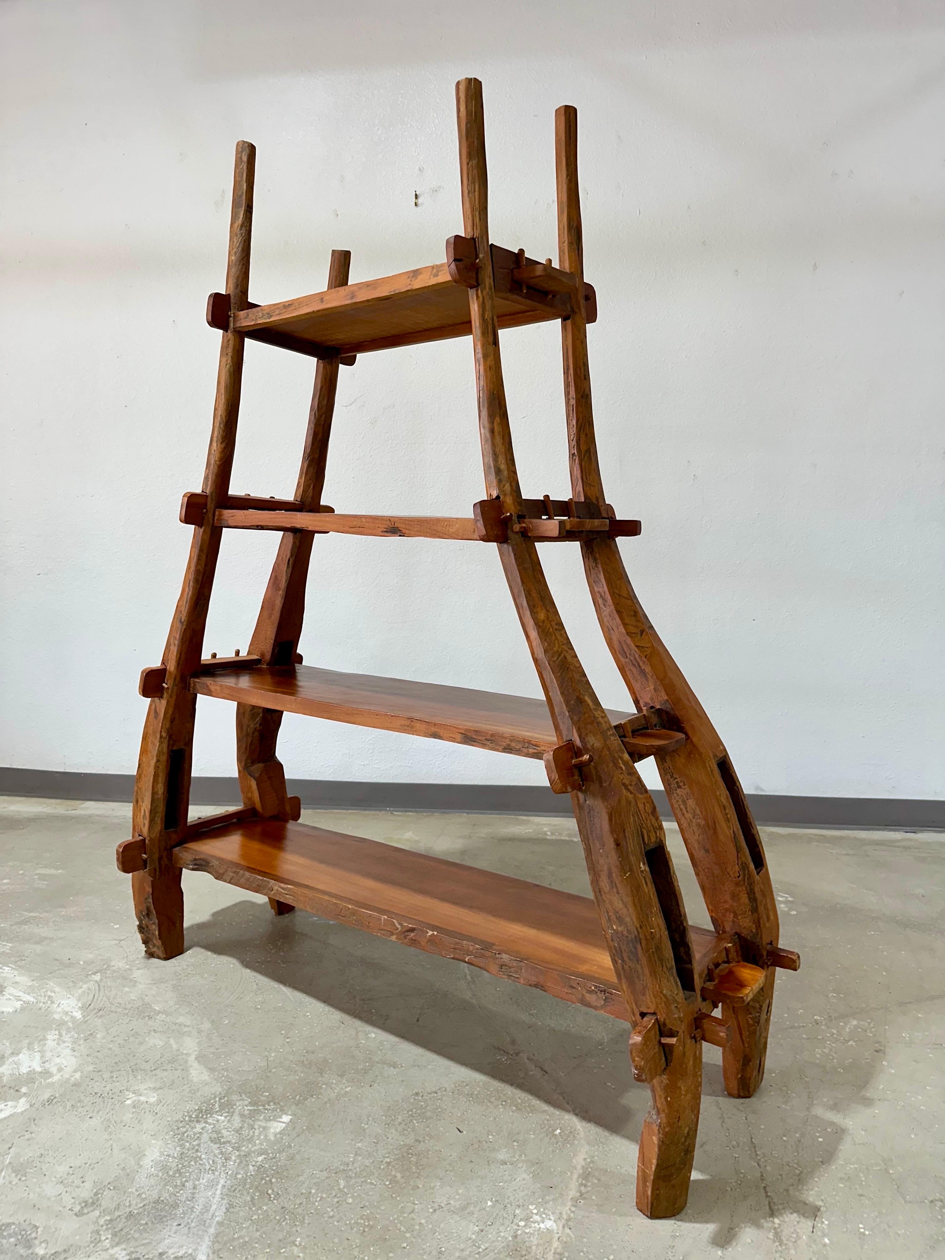Etagère ou bibliothèque en bois vintage de style primitif sculptée à la main. Origine inconnue mais probablement européenne. Jolis supports organiques courbés avec joints à tenons et mortaises et ouvertures ciselées à la main.  Quatre étagères de