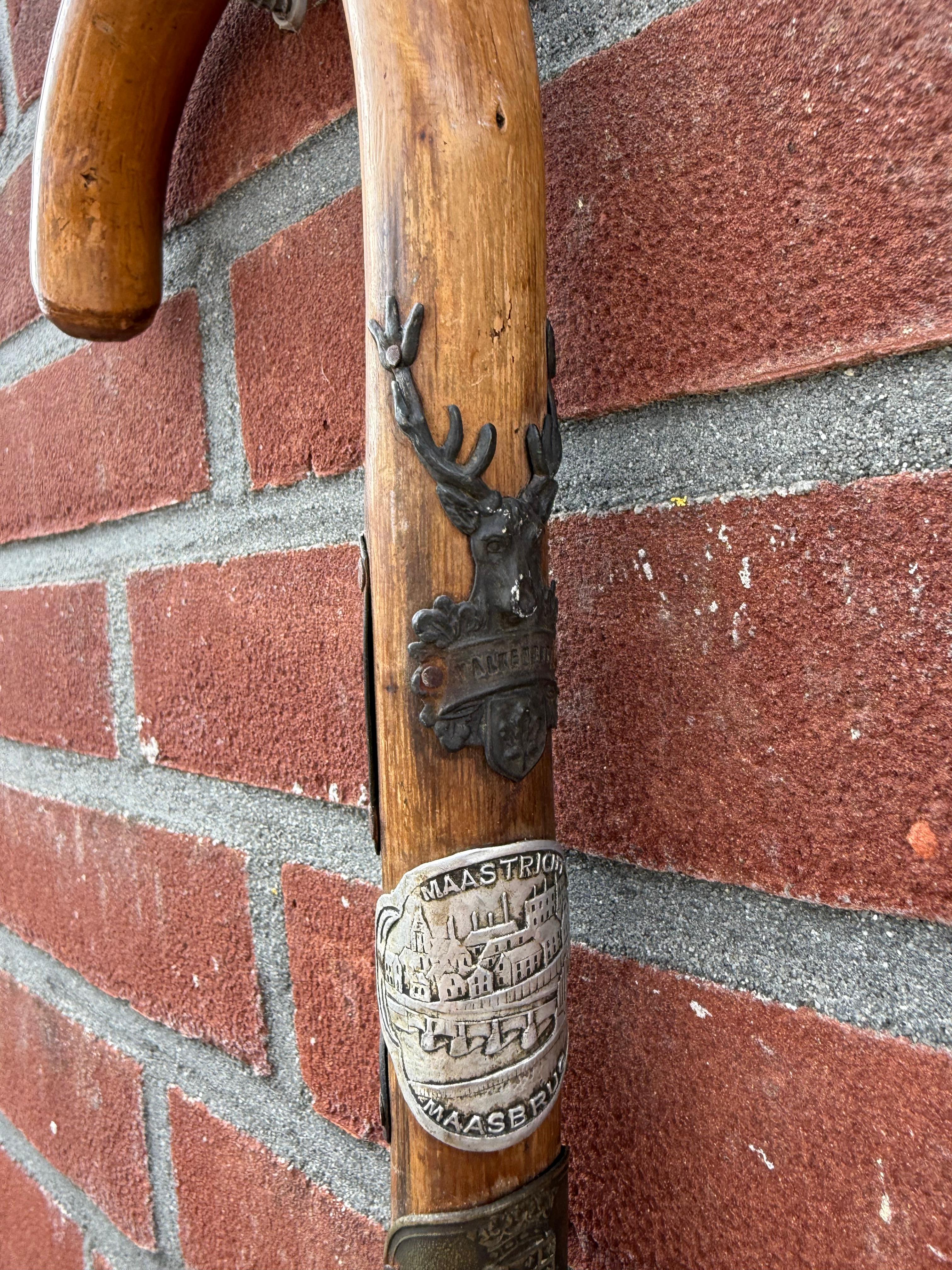 Bastone da passeggio storico adornato con targhe turistiche europee di metà secolo.

Questo affascinante bastone da passeggio in legno intagliato a mano è riccamente adornato con una collezione di distintivi di viaggio in metallo e smalto, che lo