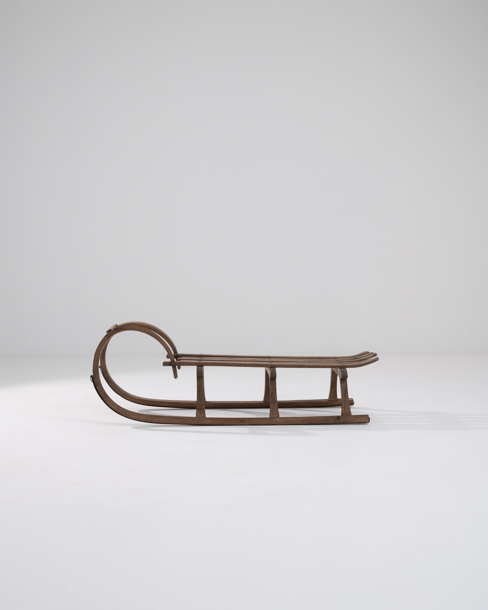A wooden sled from early 20th century Central Europe. Wooden struts composing the seat, runners, and handles have been pleasantly combined to form a toboggan sled. This classic toboggan, seemingly unaged, is ready for another race down a