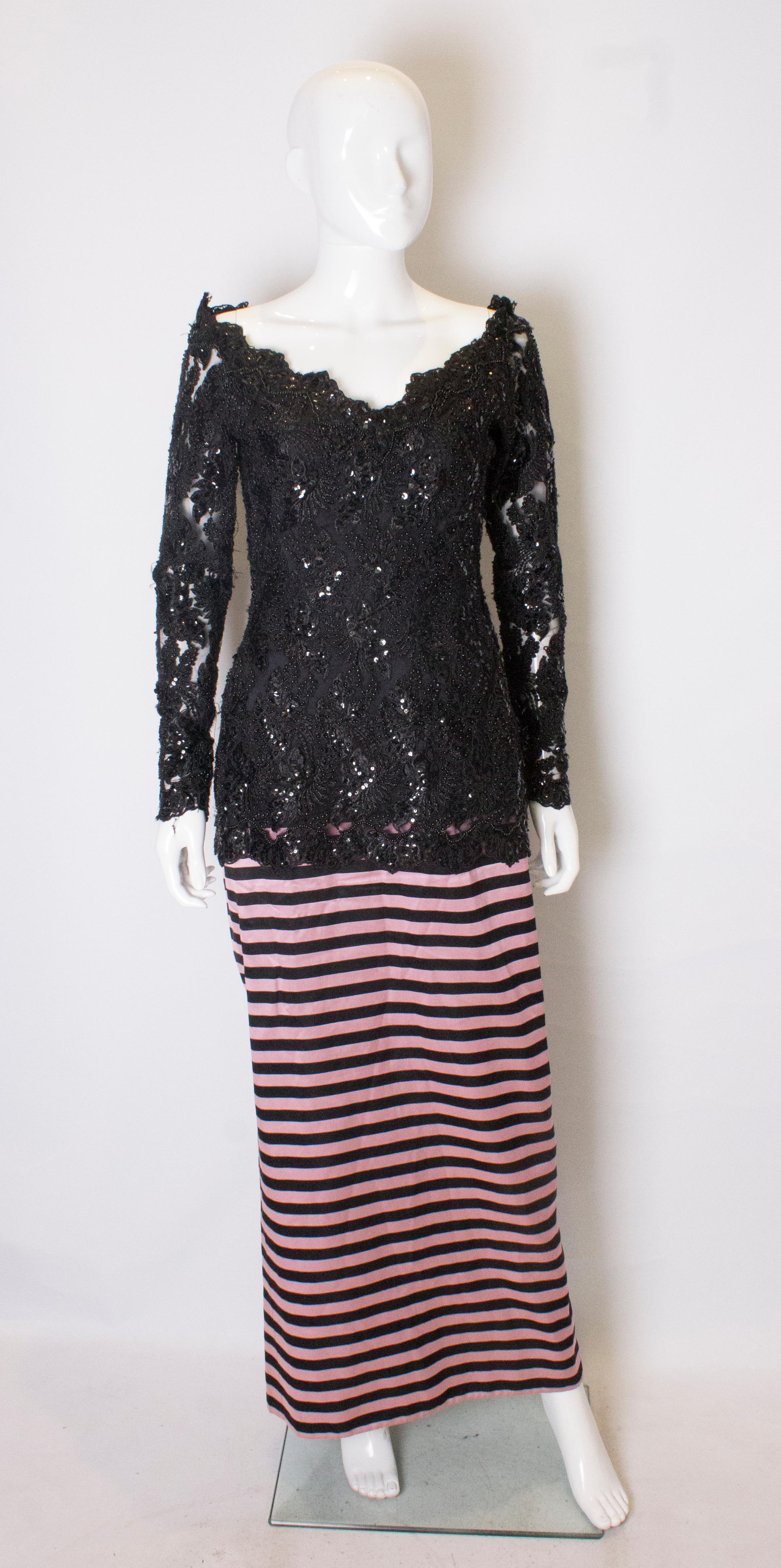 A headturning gown by Delores Couture. The upper part is heavily beaded , with a v neckline, and elastic under the shoulders, so enabling the dress to be worn off the shoulder . The skirt is in a pink and black strip with an 18'' slit at the back.