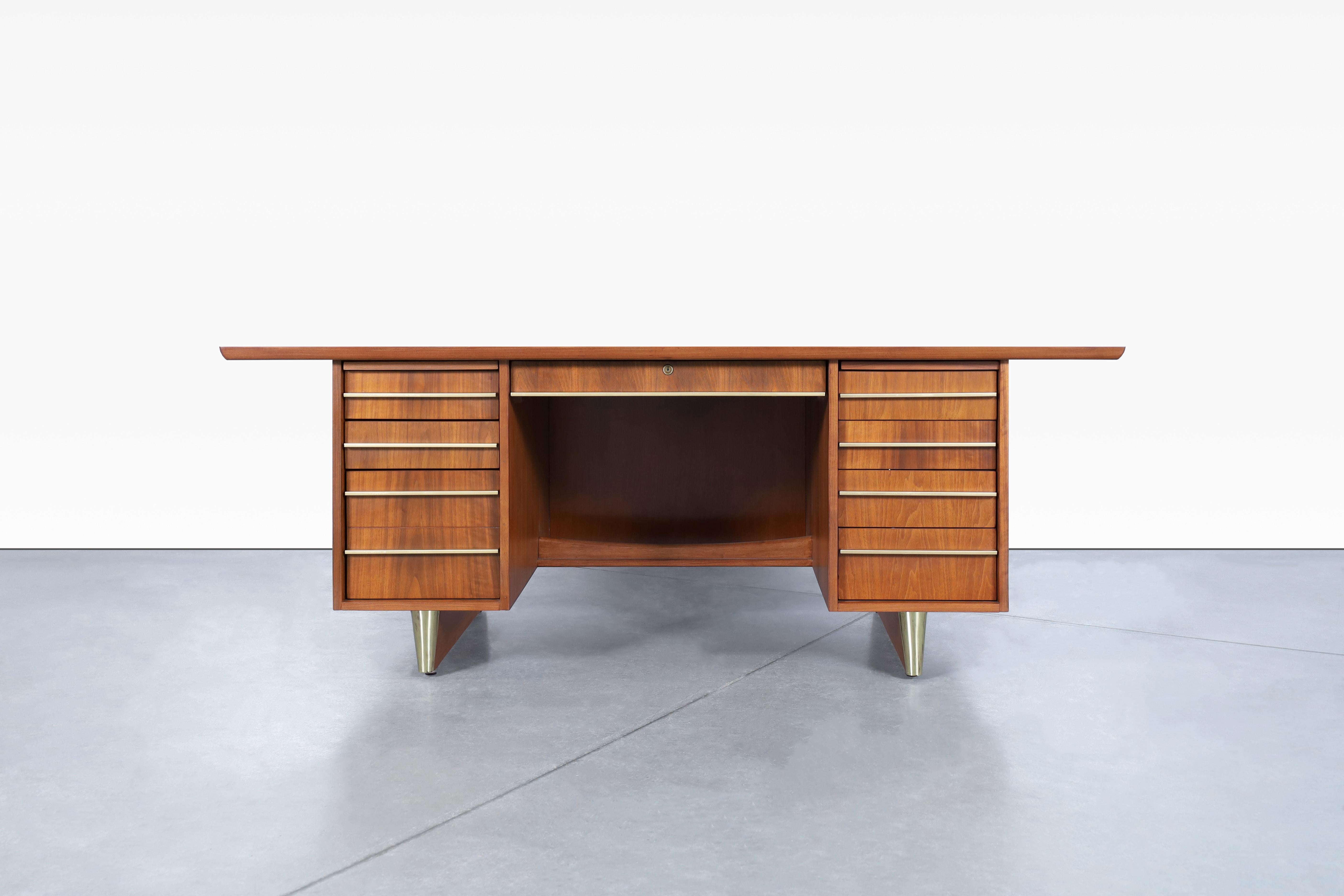 Stunning vintage executive brass and walnut desk, designed in USA, circa 1950’s. Crafted with meticulous attention to detail, this desk features meticulous design and minimalist brass handles. Designed with functionality in mind, it has six dovetail
