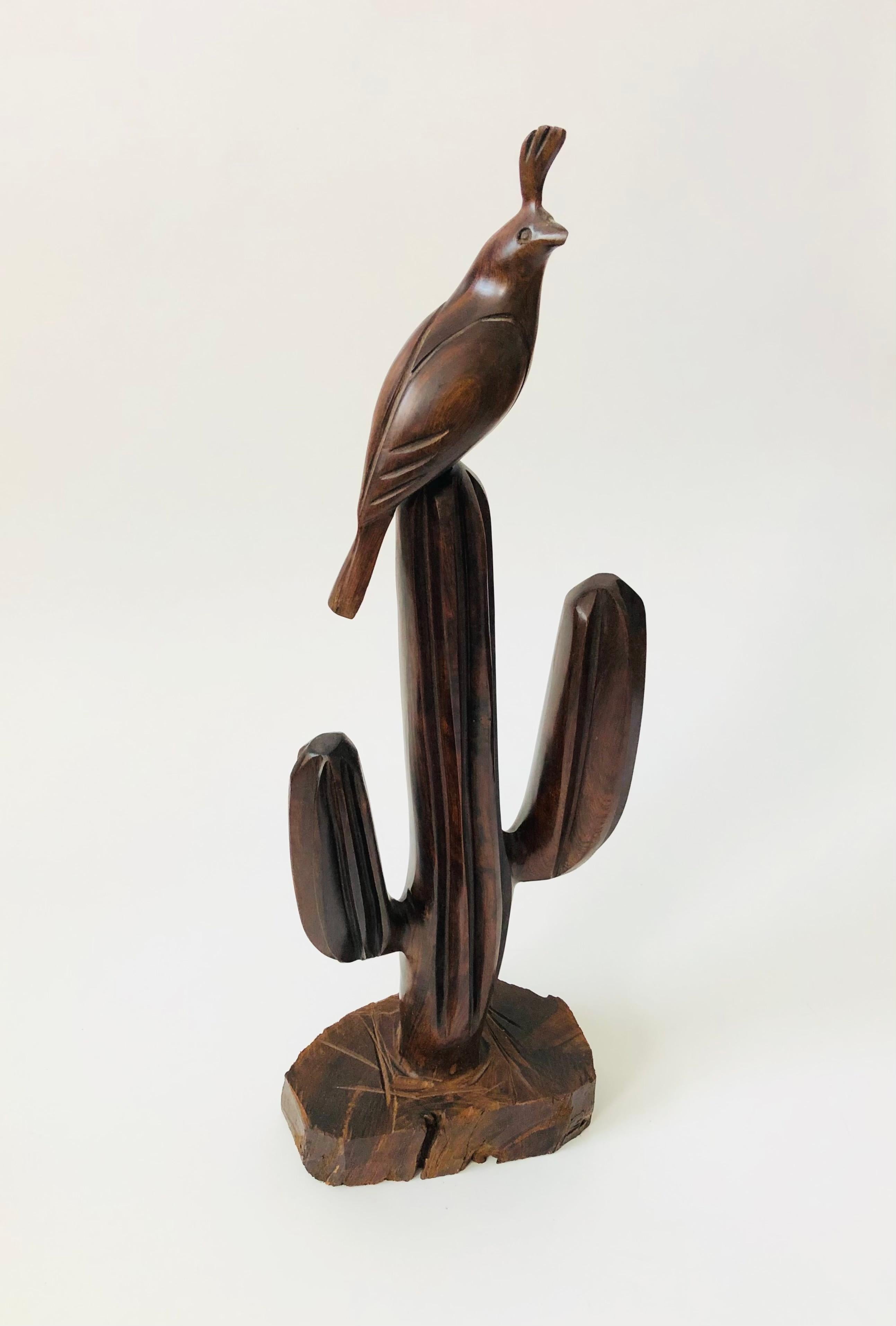 A vintage extra large carved ironwood statue in the shape of a saguaro cactus. The cactus has been carved and polished smooth with a rough natural wood base. A sweet little carved ironwood quail is perched on top of the cactus. Lovely dark natural