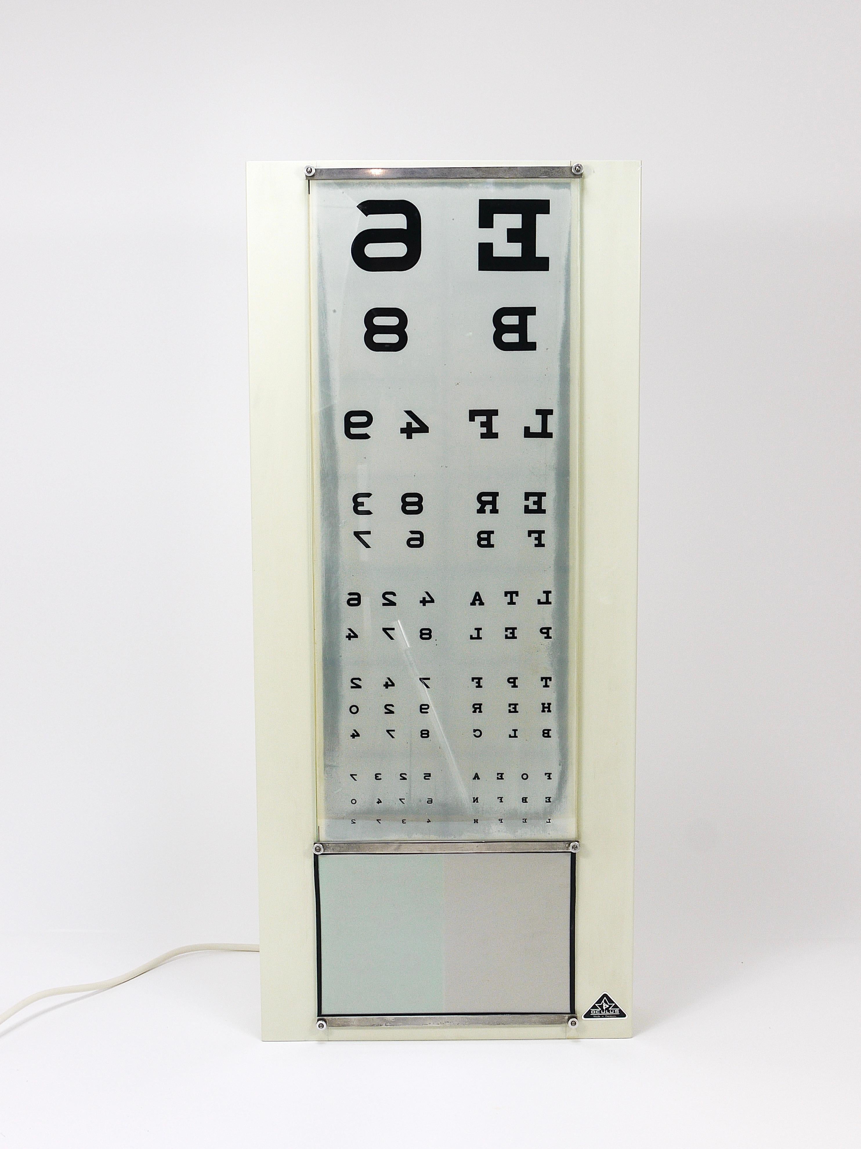A nice and decorative illuminated optometrist/ophthalmologist eye chart/Snellen chart from the 1960s, made by Oculus Germany. It features a light grey metal housing with illuminated letters and is in good condition with minimal signs of aging. The