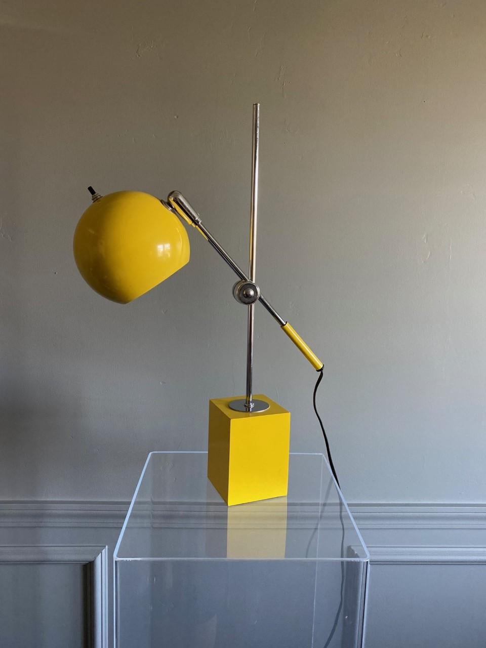 This original midcentury table lamp works with an adjustable arm and adjustable orb head supported on a steel rod that is firmly grounded on a square base. The bright yellow color adds to its cool factor. A true vintage piece that is timeless.