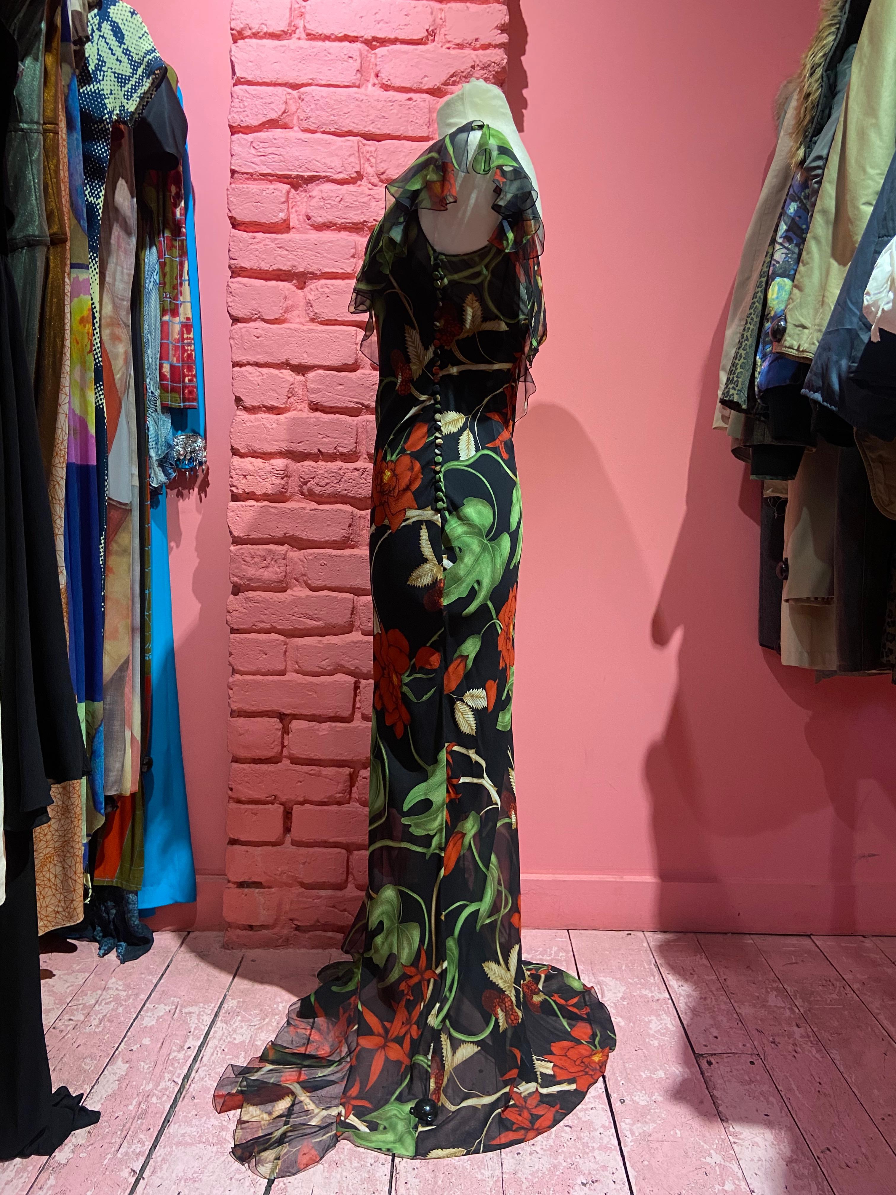We are excited to present this F/W 2002 Christian Dior by John Galliano Floral Silk Gown. The dress features a 100% silk chiffon in a red and green floral print, an asymmetrical ruffle draped from the shoulder to the bust with the other strap being