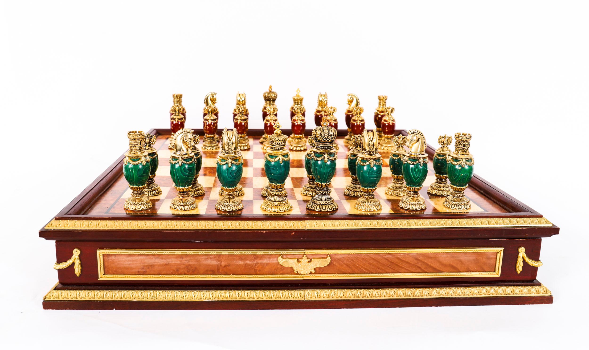 Voici un magnifique jeu d'échecs de la Maison Faberge, monté en bronze doré, en ronce de noyer et en amboyna, avec des pièces en malachite verte et en marbre rouge. L'ensemble a été réalisé par Franklin Mint à la fin du 20e siècle.
 
L'échiquier