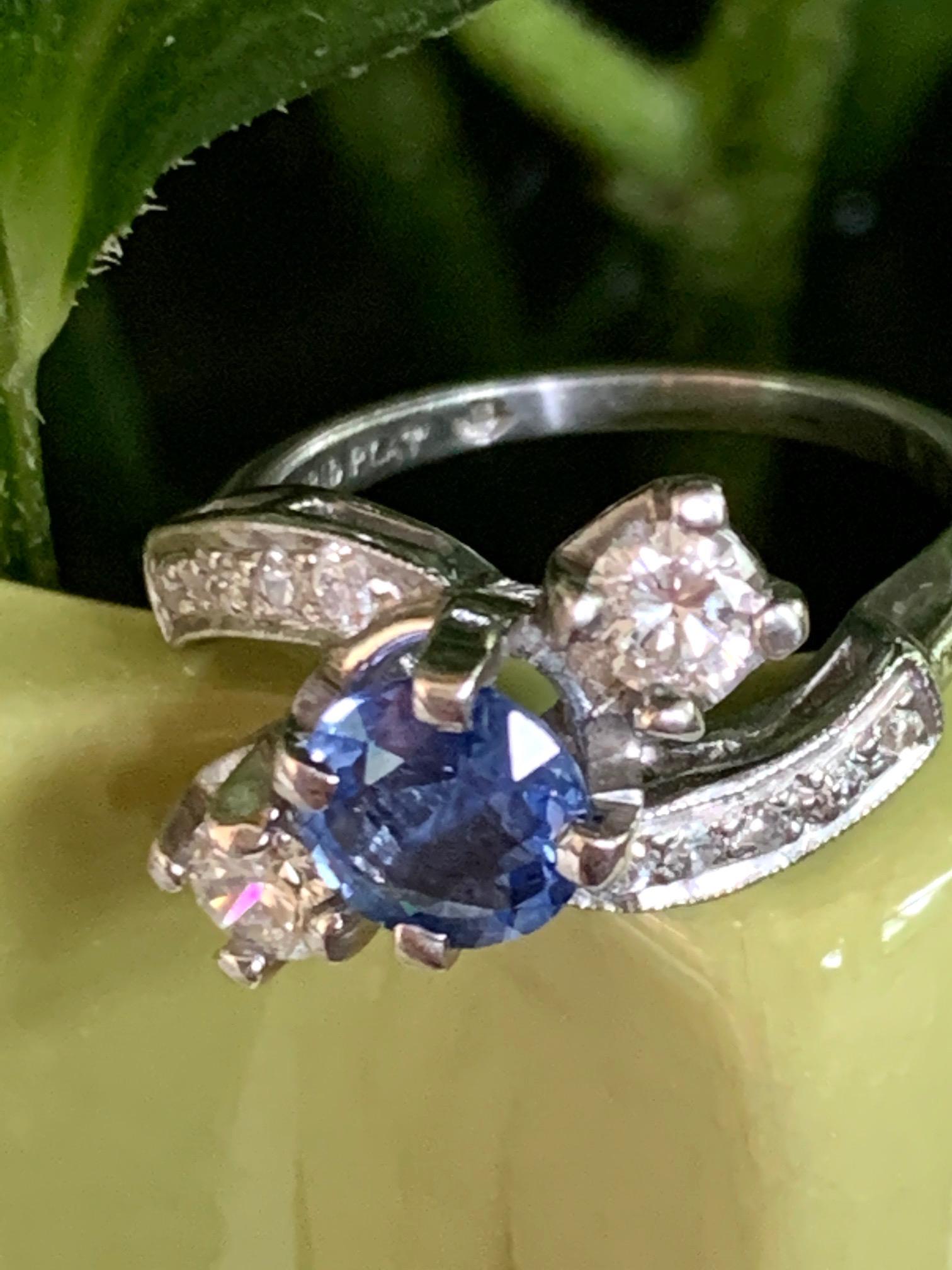 This beautiful ring features a faceted, medium blue Sapphire as the center stone. It is approximately 1.30ct.  This center stone is accented by two 4mm brilliant cut side Diamonds and ten 1.5mm single cut side Diamonds. The total estimated Diamond