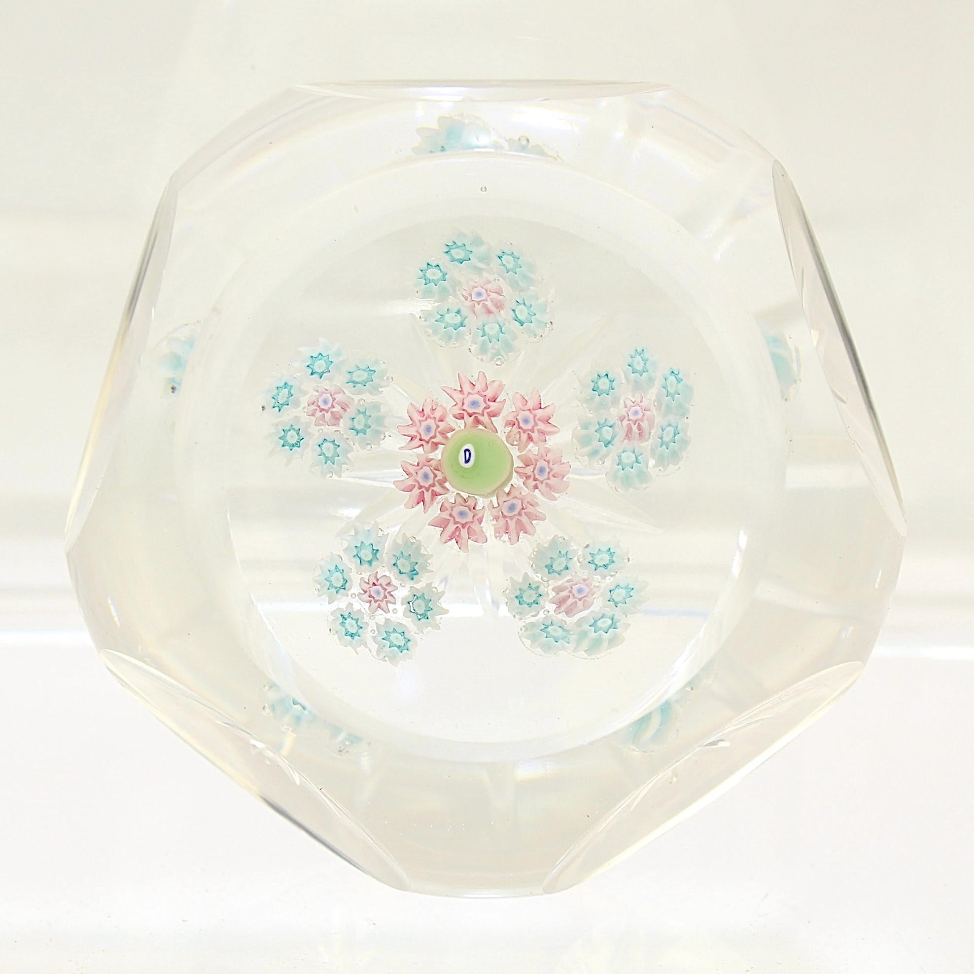 A fine faceted Perthshire spaced millefiori art glass paperweight.

It has pink and light blue canes centered on a 1972 'D' date cane.

The base has a star cut pontil mark.

Date:
1972

Overall condition:
It is in overall good,