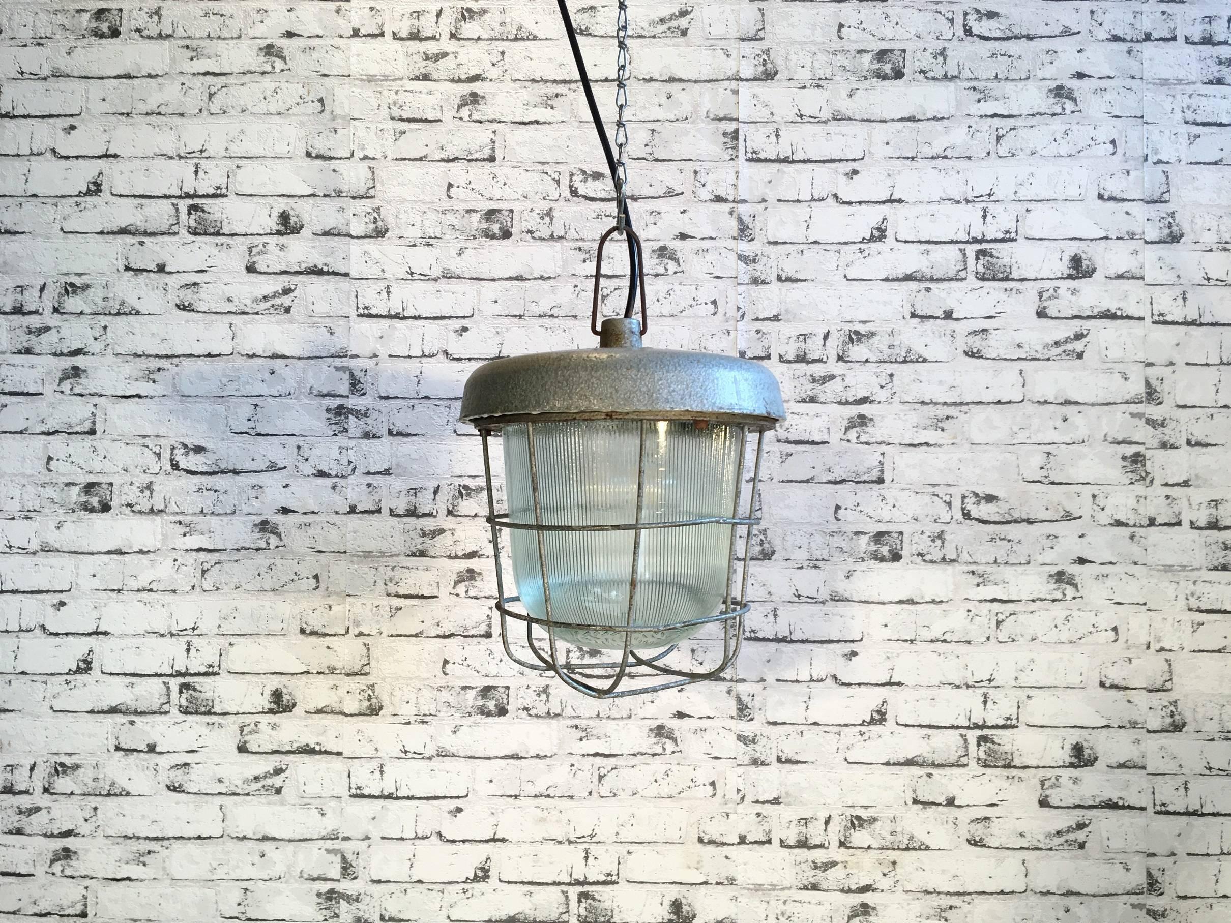 This vintage factory industrial hanging lamp was designed in the 1960s in Poland. It is made from cast iron and striped glass.
New socket E 27 and wire. Very good vintage condition. Weight: 7 kg.