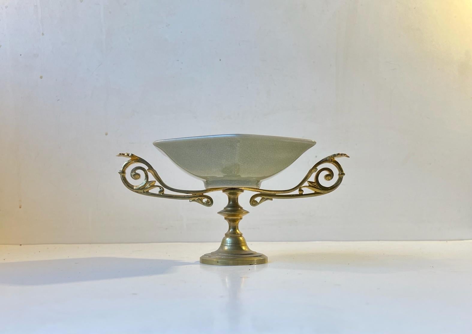 Small stylish pedestal for bonbons, chocolates, cookies or sugar. Craquele tin-glazed bowl with hand-painted floral, gold glaze motif and an intricate brass base with fine details. Designed and manufactured at Royal Copenhagen in Denmark during the