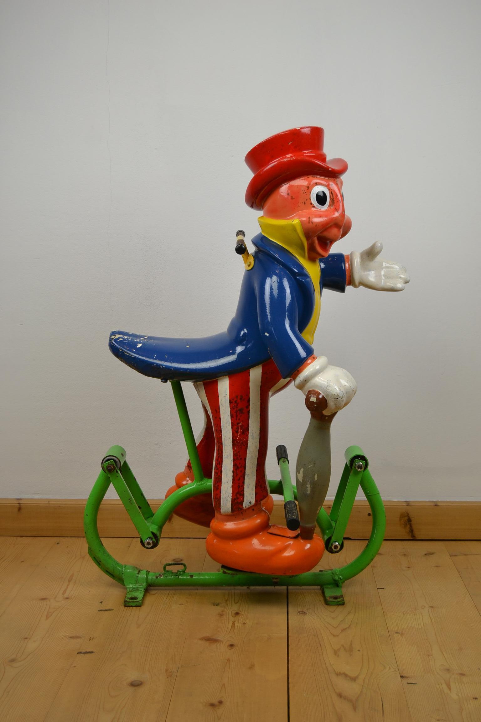 Cute looking Fairground figurine - Carnival figure, 
Jiminy Cricket - a Disney Character - mounted on an iron swing. 
This awesome polyester figure - known from the Animated Cartoon and Books - dates late 1960s.

This Children's Carnival Ride,
