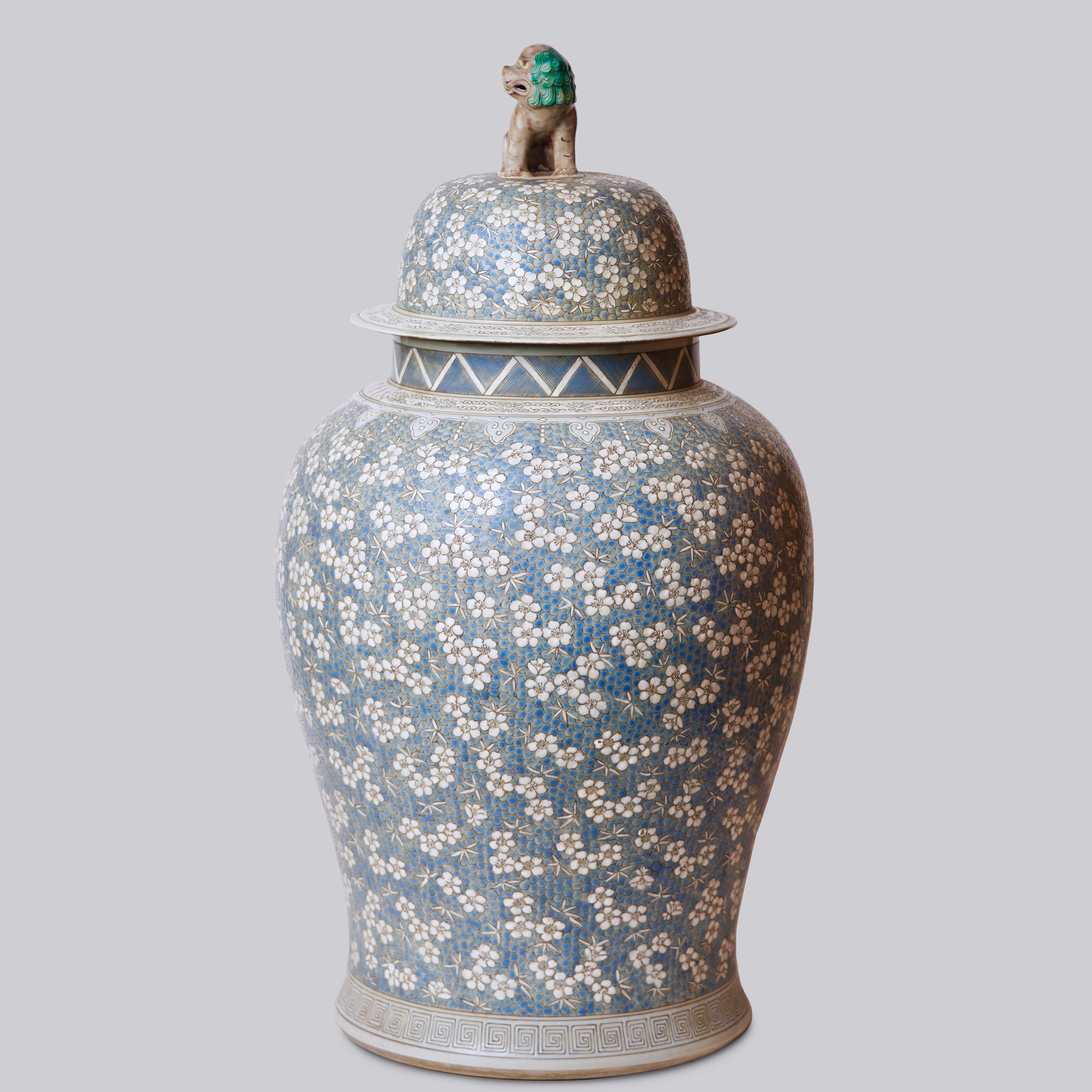 This temple jar is a traditional porcelain vessel from Jingdezhen, a town long distinguished by imperial patronage. An uncommon blue and grey pebbled and textured field contrasting with soft white cherry blossoms sets this vase apart from the usual